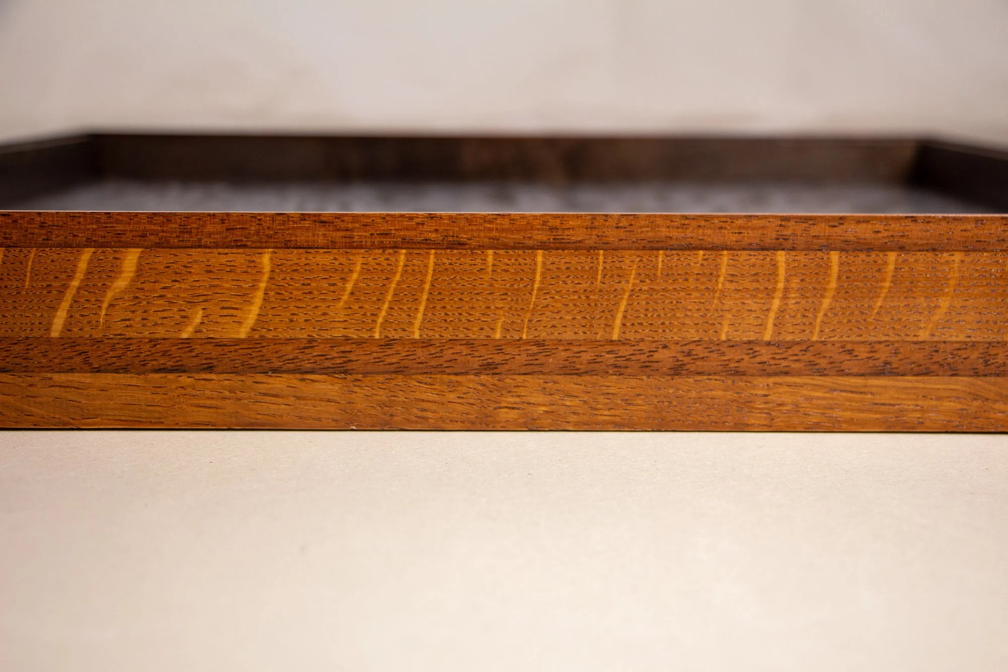 Turbulent Aegis 001 frame detail: frontal side view of the handcrafted frame, emphasizing the horizontal wood grain, tonal banding, and the warm-to-dark structural rhythm.