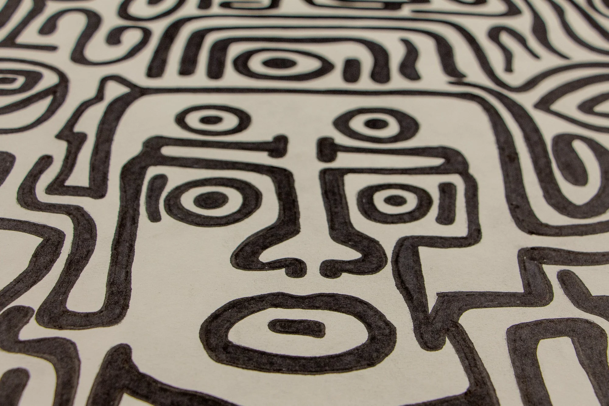 Resonant Syntax 003 detail: frontal close-up of the central mask, with four circular eyes arranged in two tiers, a geometric nose, and an oval mouth; dense black linework framed by surrounding contours