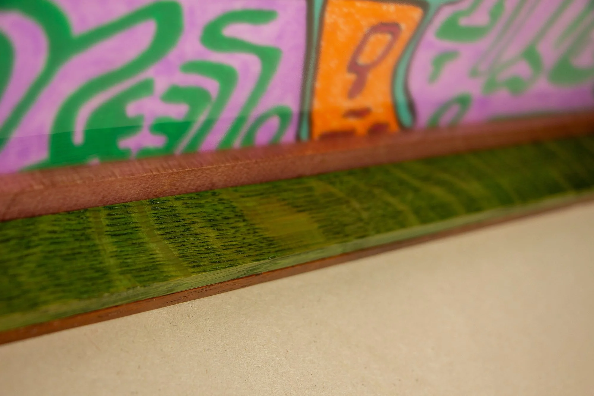 Unseen Signifiers 002 frame detail: low angled close-up along the lower inner edge of the frame, emphasizing the reddish inner spacer, green-stained band, and the reflective glass surface above. mahogany, oak and beech wood.