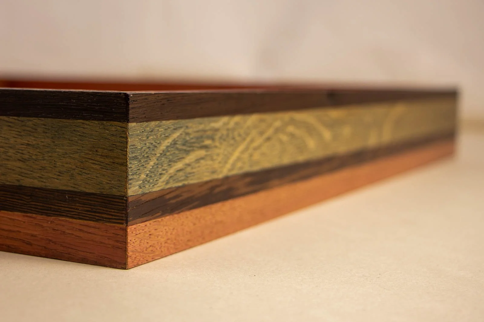 Silence’s Caesura 003 frame: outside corner, slim dark cap, broad blue and pink washed oak field, mocha divider, and warm mahogany base; satin sheen