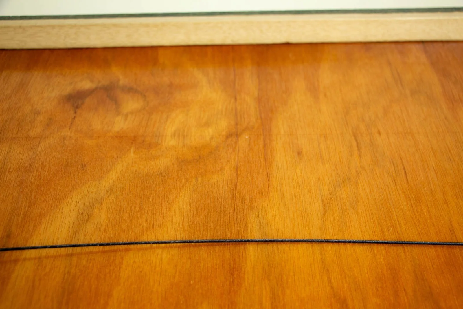 Silence’s Caesura 002 frame: back panel, warm honey-toned plywood with a quiet grain; the hanging wire runs taut and level