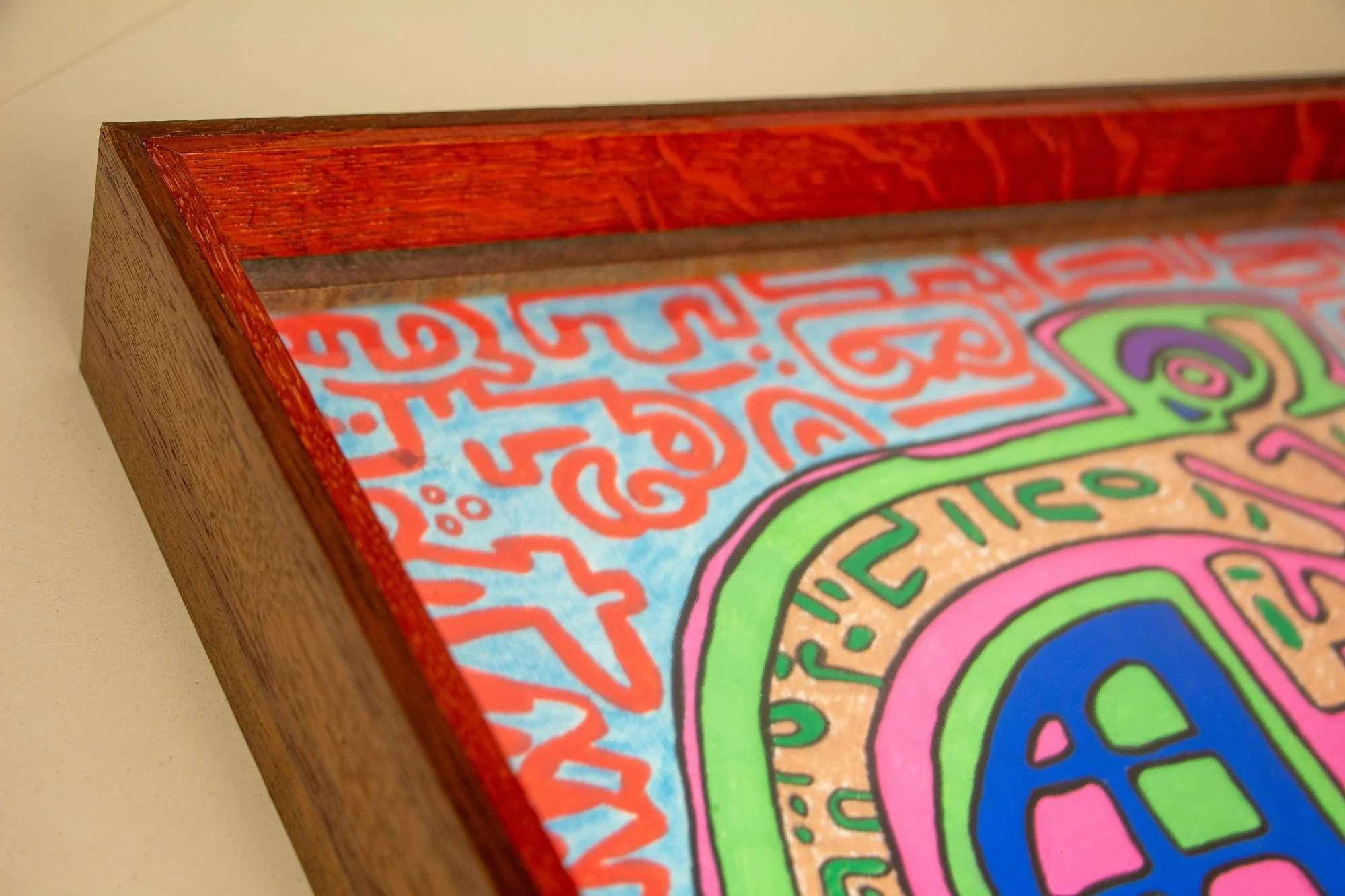 Close-up of a colorful abstract drawing inside a wooden frame.