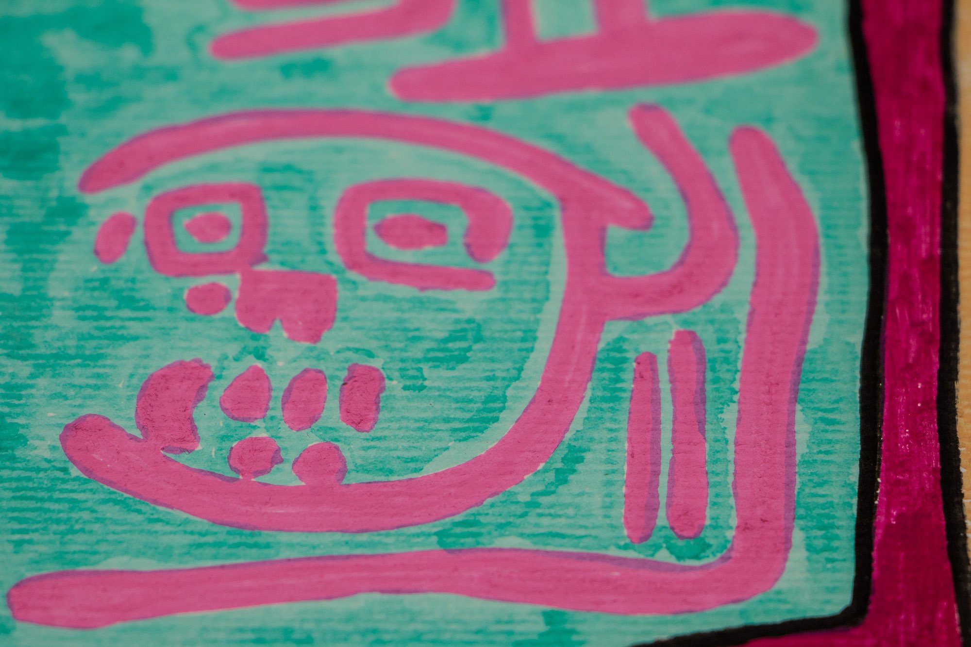 Unseen Signifiers 004 detail: boxed symbol detail in pink on turquoise, showing two mask-like forms and angular surrounding marks within the larger symbolic field.