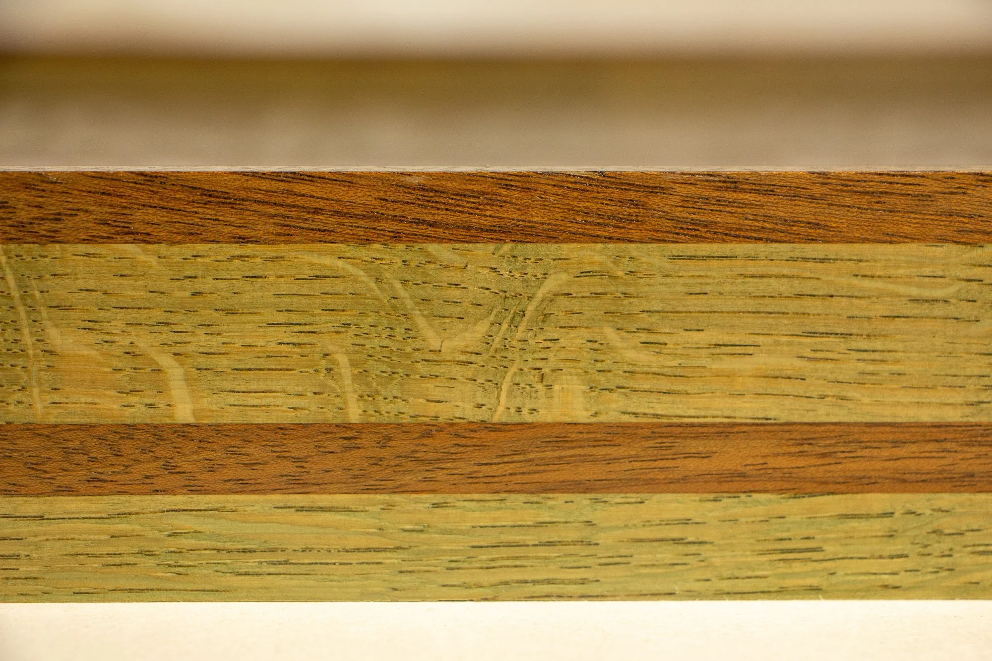 Close-up of layered wood; oak and mahagony,  with a light-colored central strip and darker outer layers.