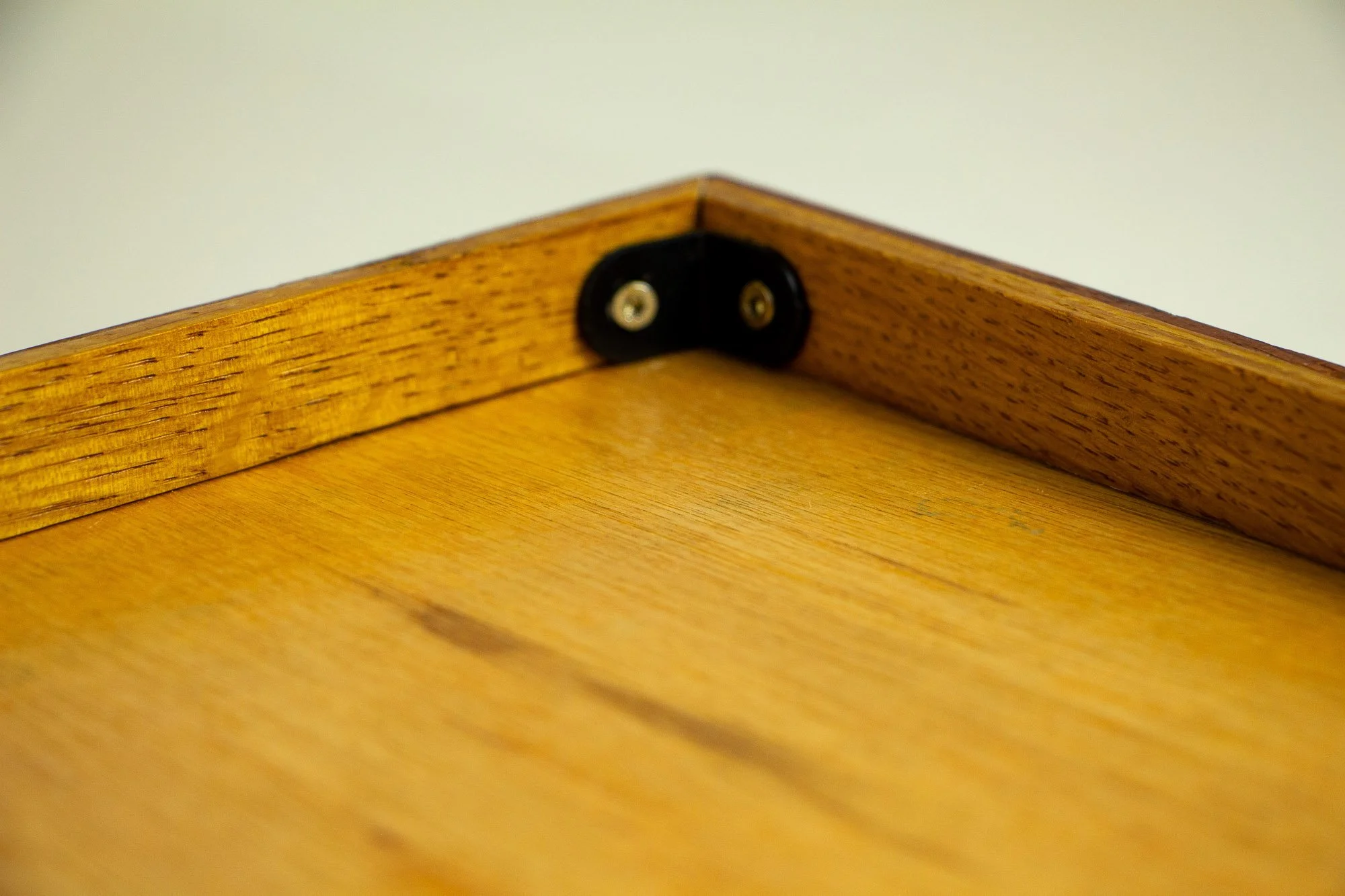 Turbulent Aegis 002 frame detail: rear view of the frame corner with backing panel, showing the wood grain of the back panel, inner support strip, and black corner bracket assembly.