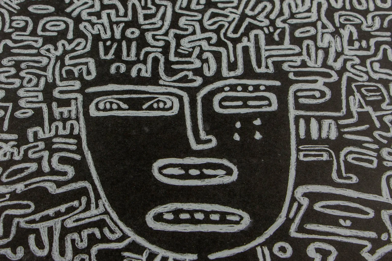 Synaptic Mythos 002 detail: central mask, tablet eyes, two stacked mouths, and three tear marks on the right cheek; dense glyph “hair” crowds the forehead; chalk-white on matte black with soft halos