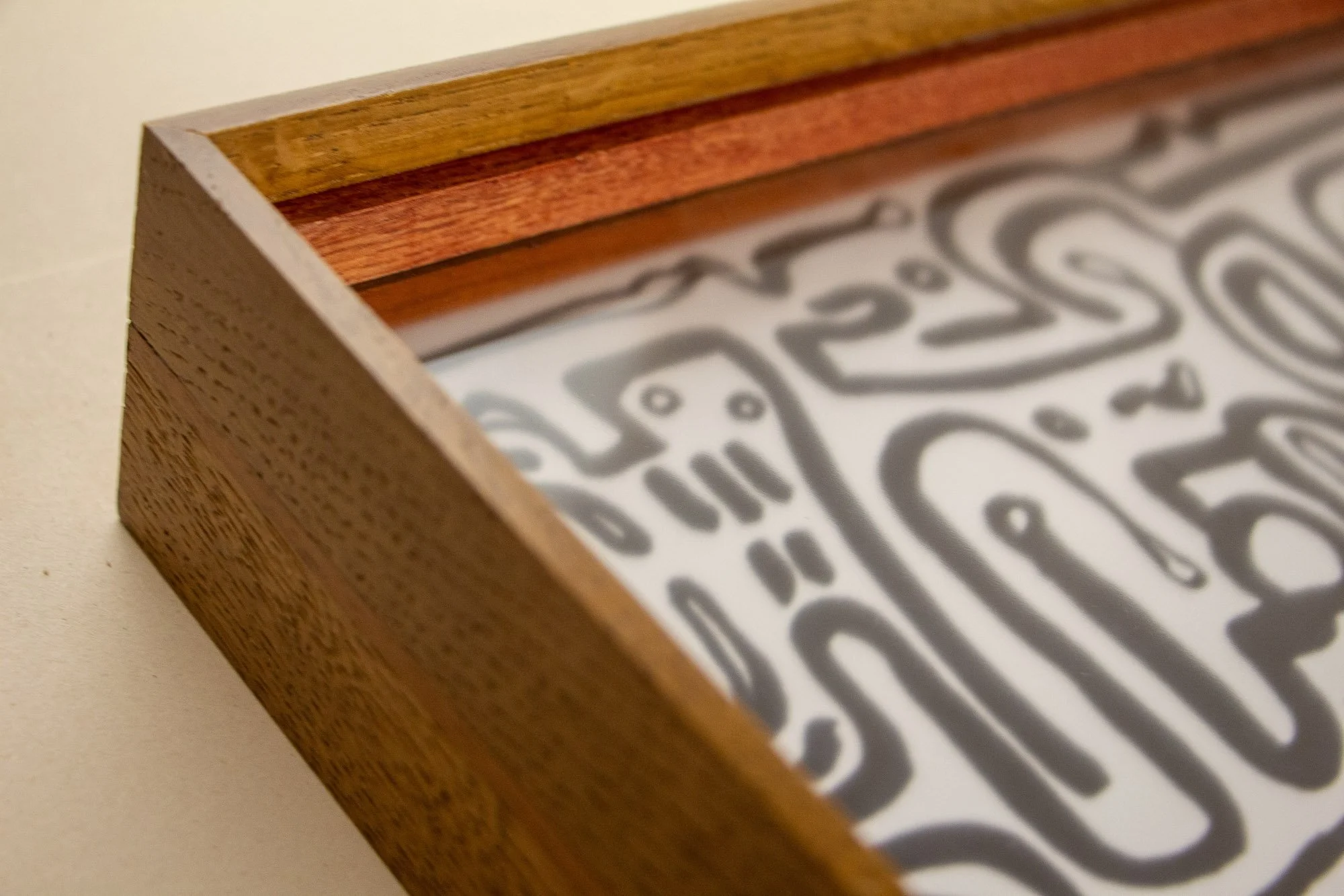 Veiled Alchemist 001 frame detail: close-up along the inner edge of the frame, showing the Japanese elm outer section, the reddish inner band, the recessed glazing, and the subtle depth created by the layered construction.