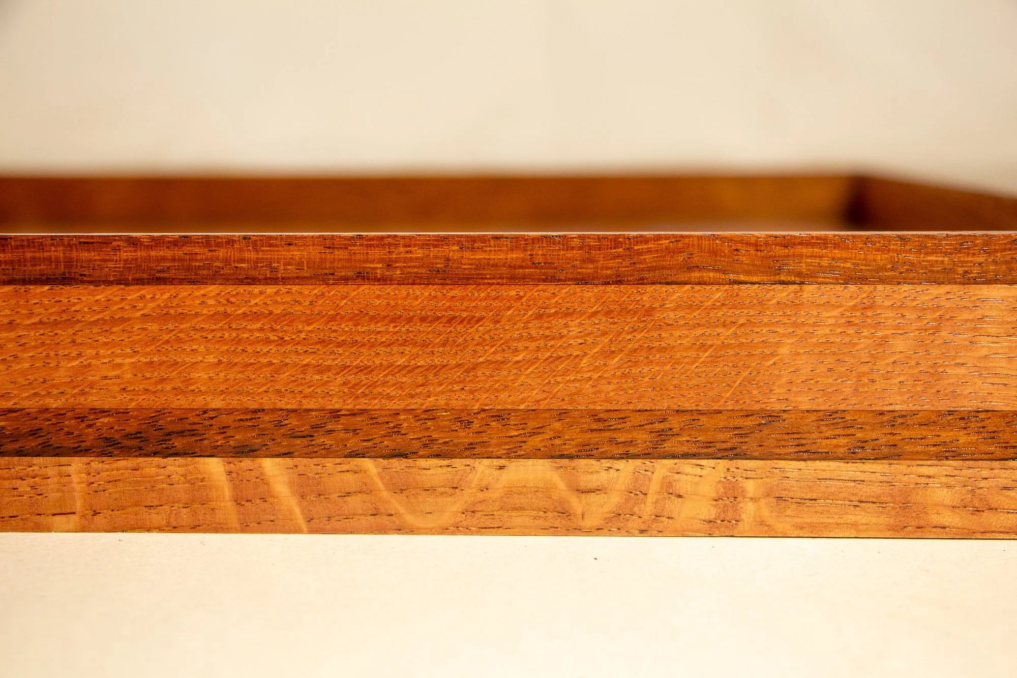 Close-up view of a wooden shelf with a plain beige wall in the background.