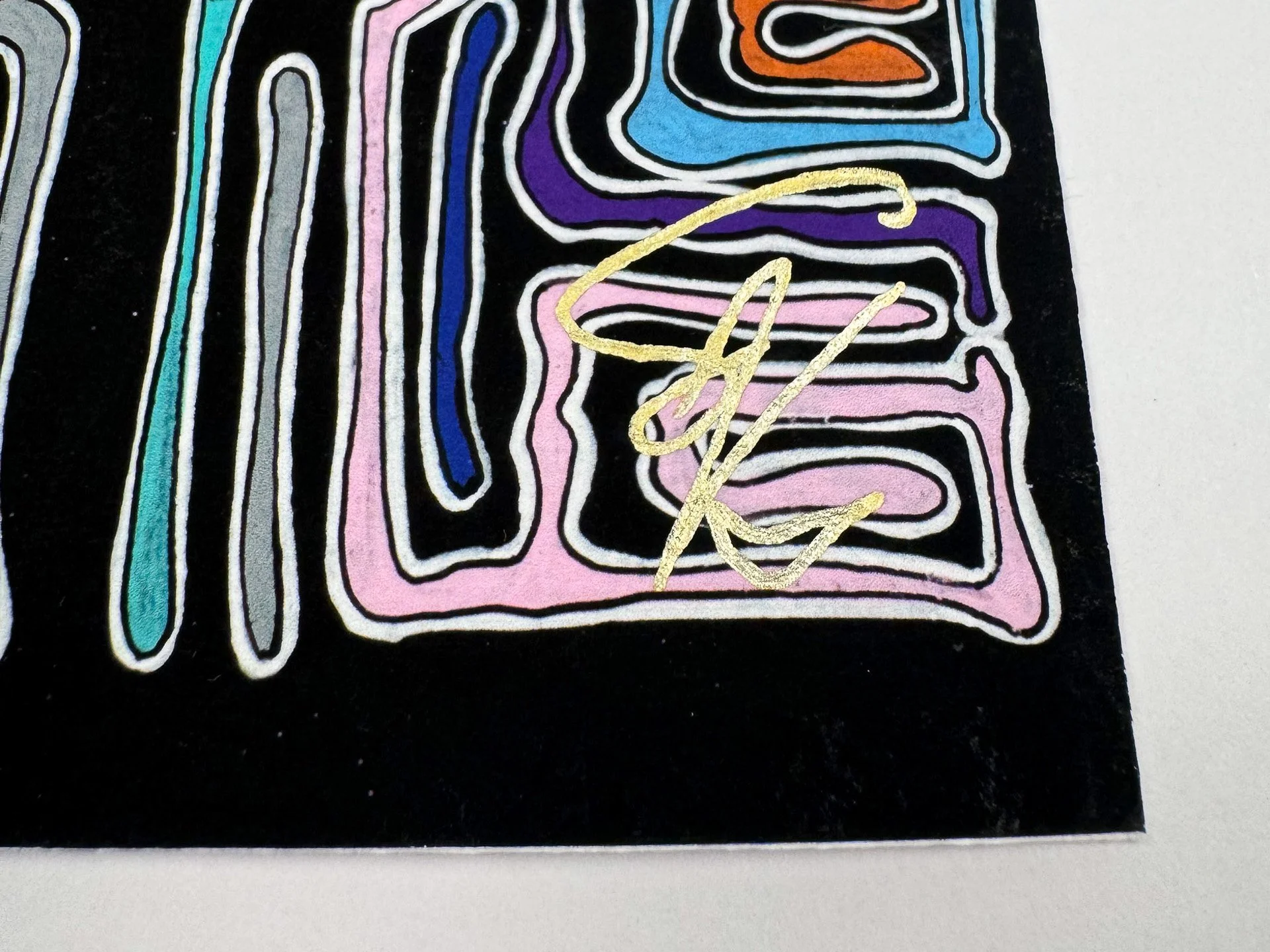 Bottom right corner detail showing the gold artist signature over pink, violet, blue, and grey maze-like lines on black, emphasizing the hand-finished surface and edge of the work.