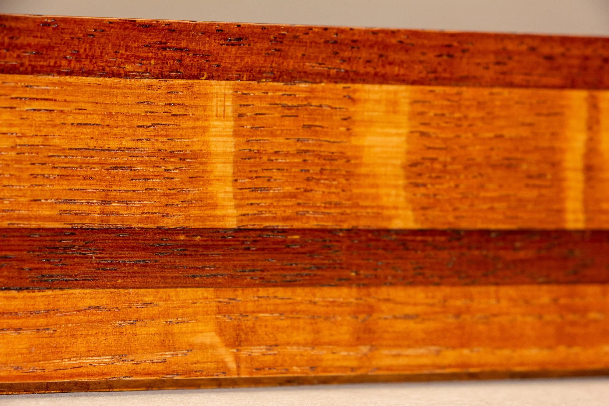 Turbulent Aegis 002 frame detail: extreme close-up of the frame’s side surface, emphasizing the horizontal wood grain, subtle tonal shifts, and the rhythm of the layered construction.
