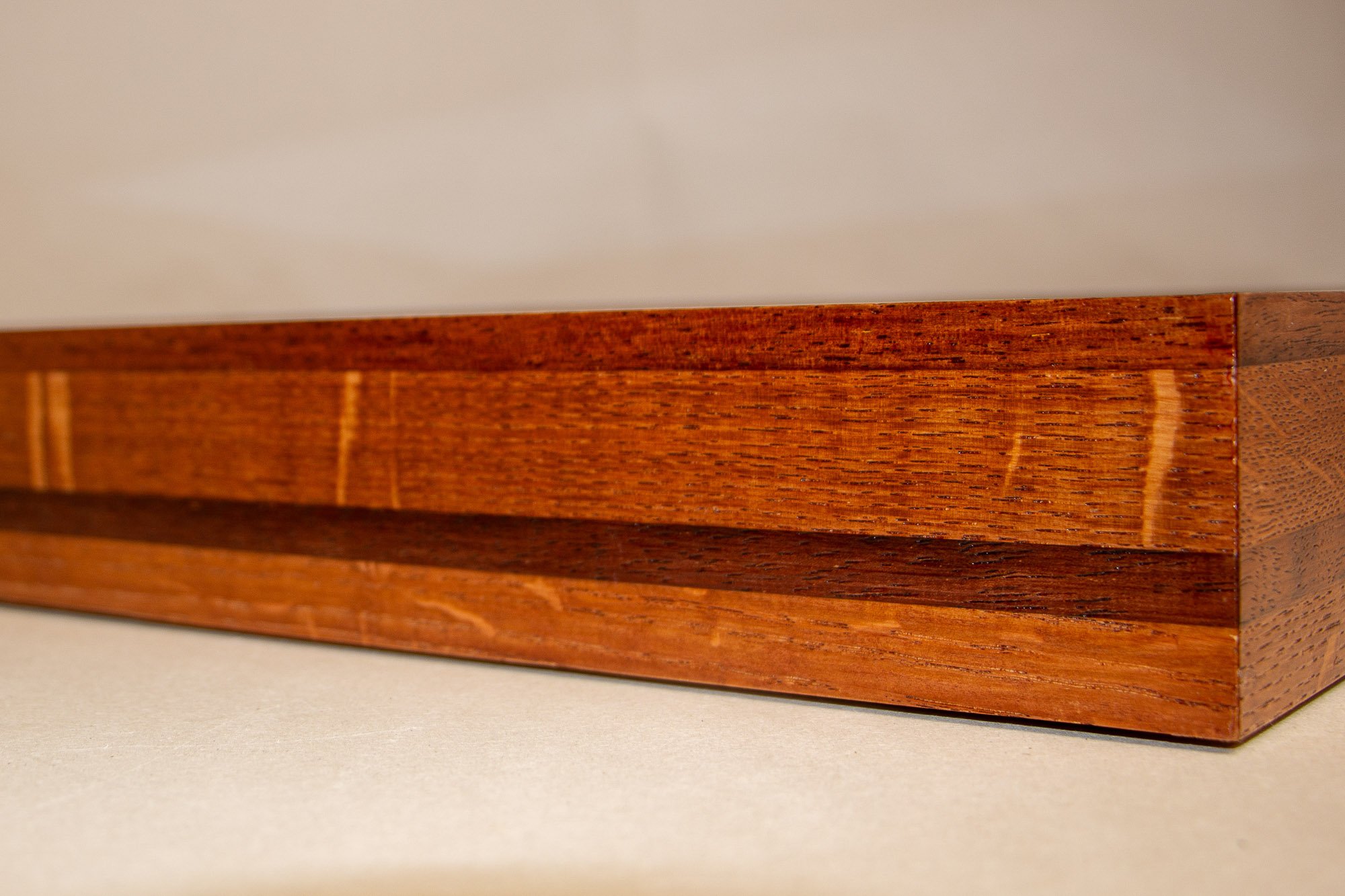 Turbulent Aegis 002 frame detail: oblique side view of the handcrafted frame, showing the elongated profile, warm lacquered sheen, and the layered bands running across the full length.