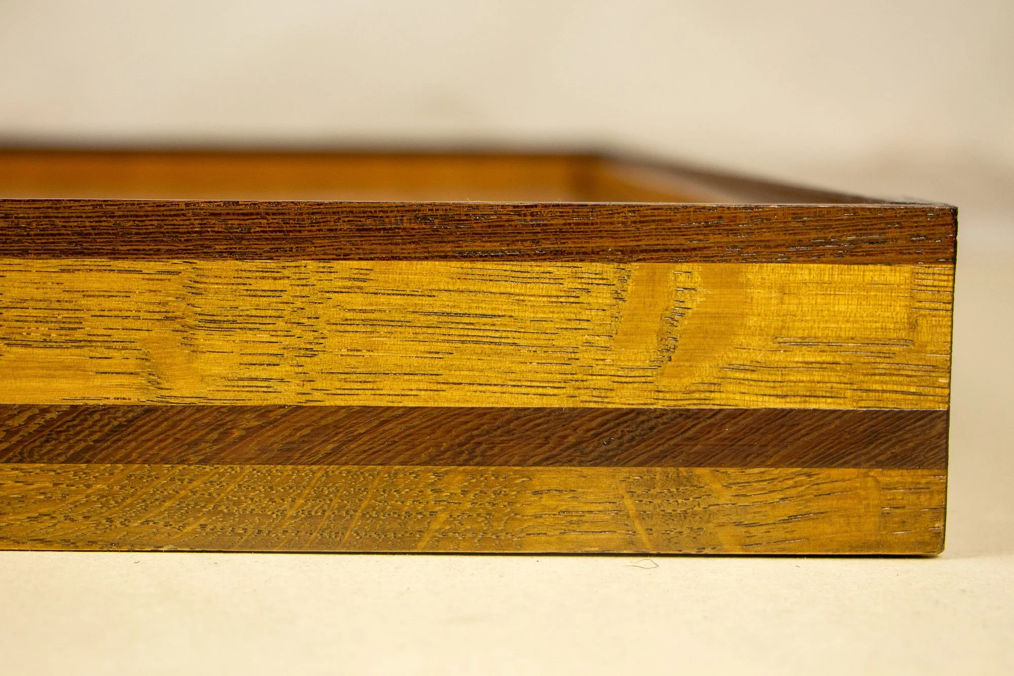 Elusive Cocoon 002 frame: angled side detail of the frame construction, emphasizing the layered profile, the warm golden oak-toned band, and the darker upper edge.