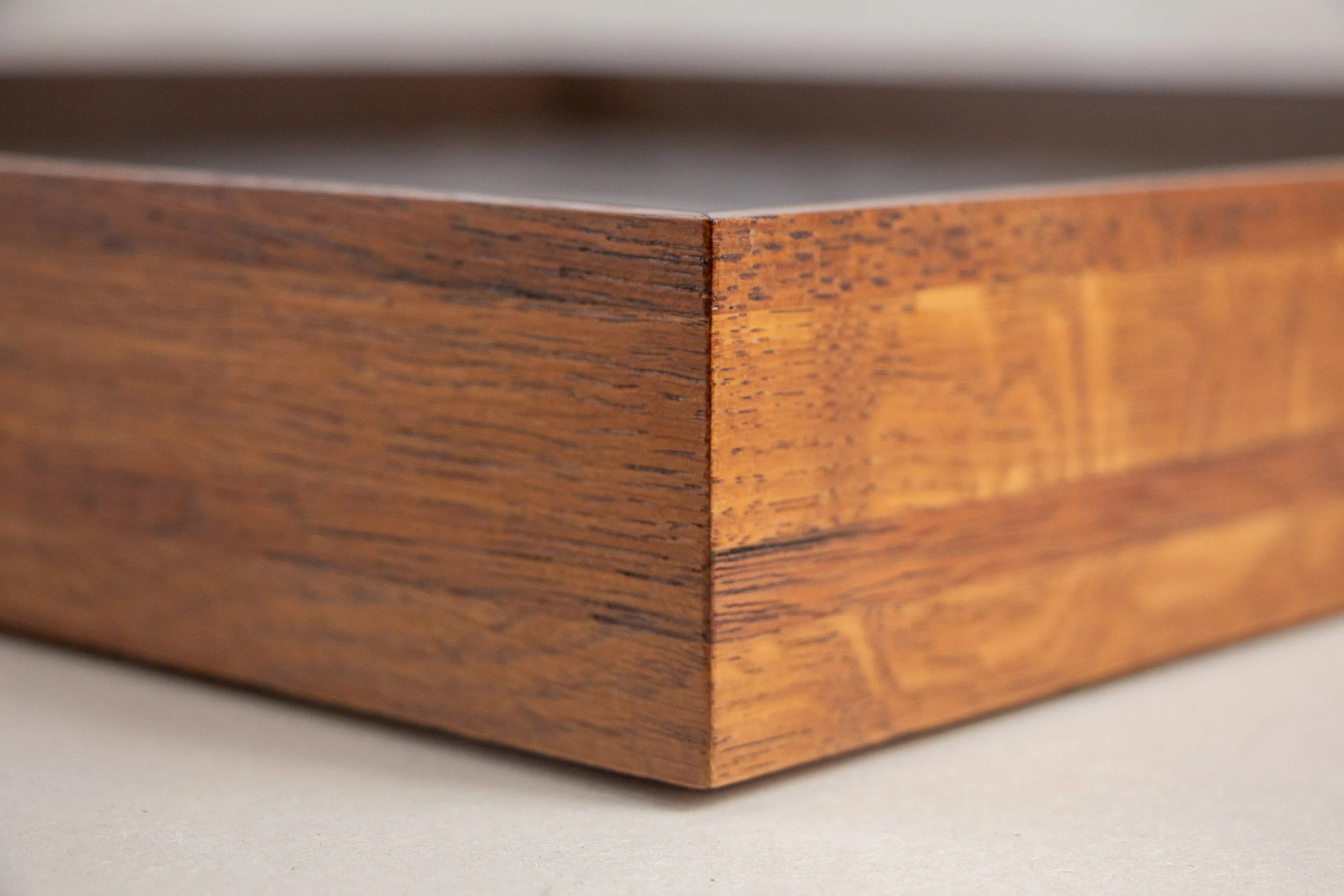 Turbulent Aegis 003 frame detail: close-up of the handcrafted corner joint, showing the clean miter, warm amber-brown wood tones, visible grain, and the subtle depth of the layered frame profile.