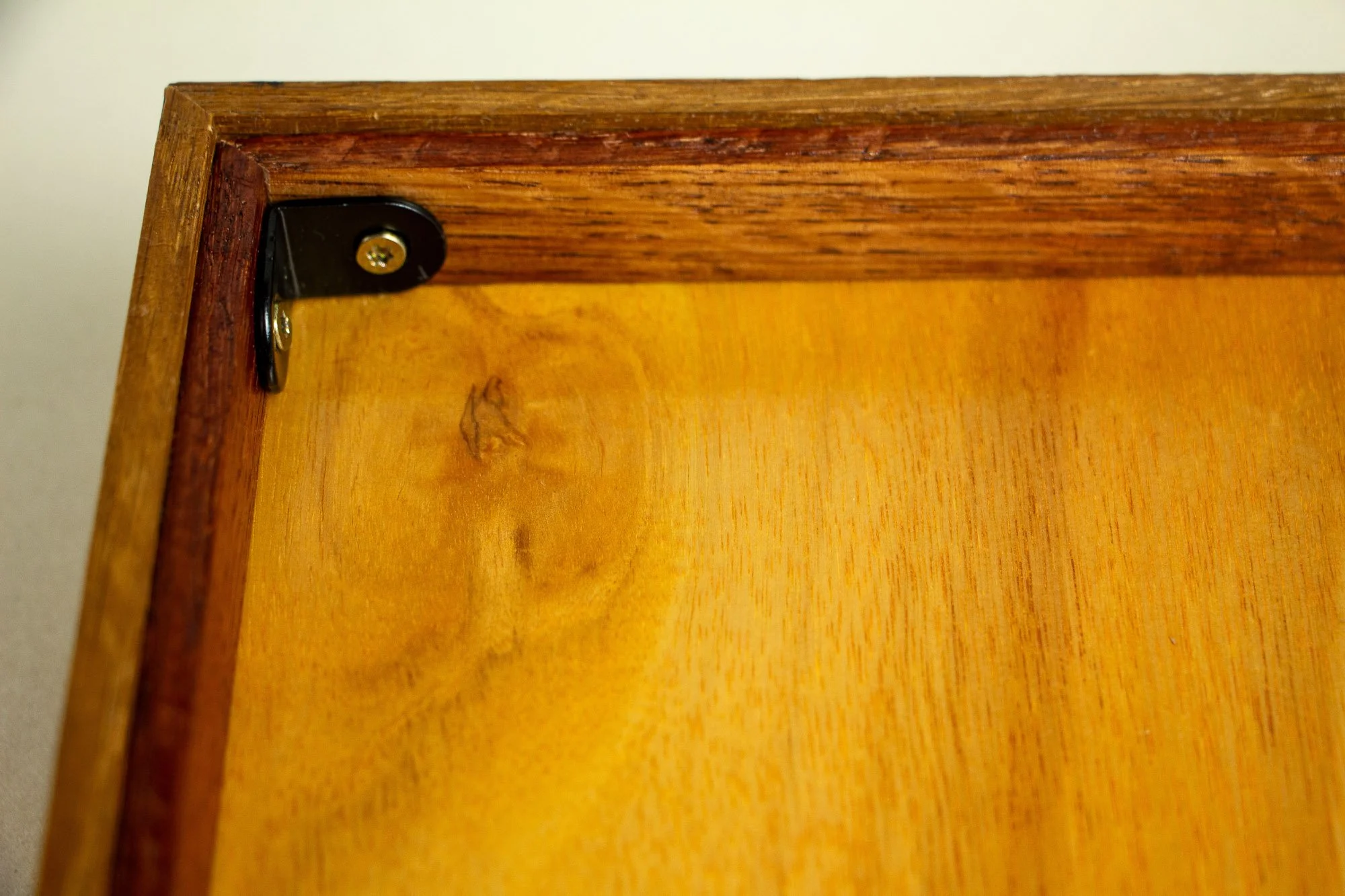 Unseen Signifiers 008 back detail: close-up of the rear corner bracket, showing the black metal corner support fixed to the wooden back panel and frame.