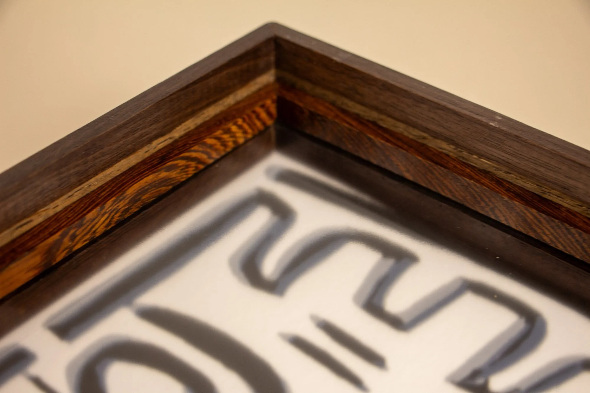 Luminous Parallax 002 frame: top corner detail of the framed work, showing the mitered join, the dark layered construction, and the artwork softening beneath the glass.