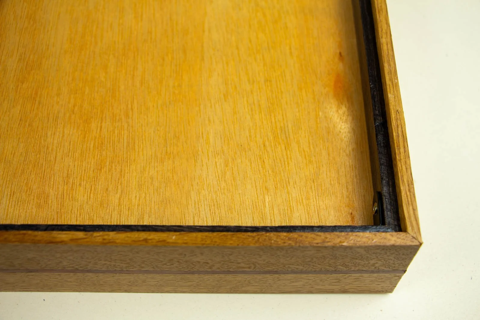 Golden Nostalgia 004 frame: rear panel, golden wood backing with visible grain and small knot; dark-stained inner liner along the top edge