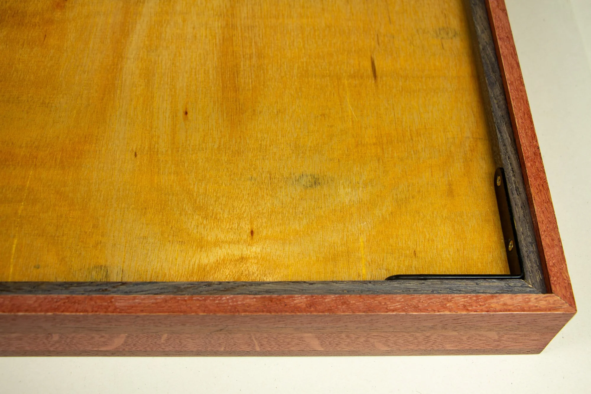 Resonant Syntax 003 frame: reverse detail of the back construction, with meranti plywood back panel, dark granada-toned inner rim, black metal corner bracket, and red outer frame