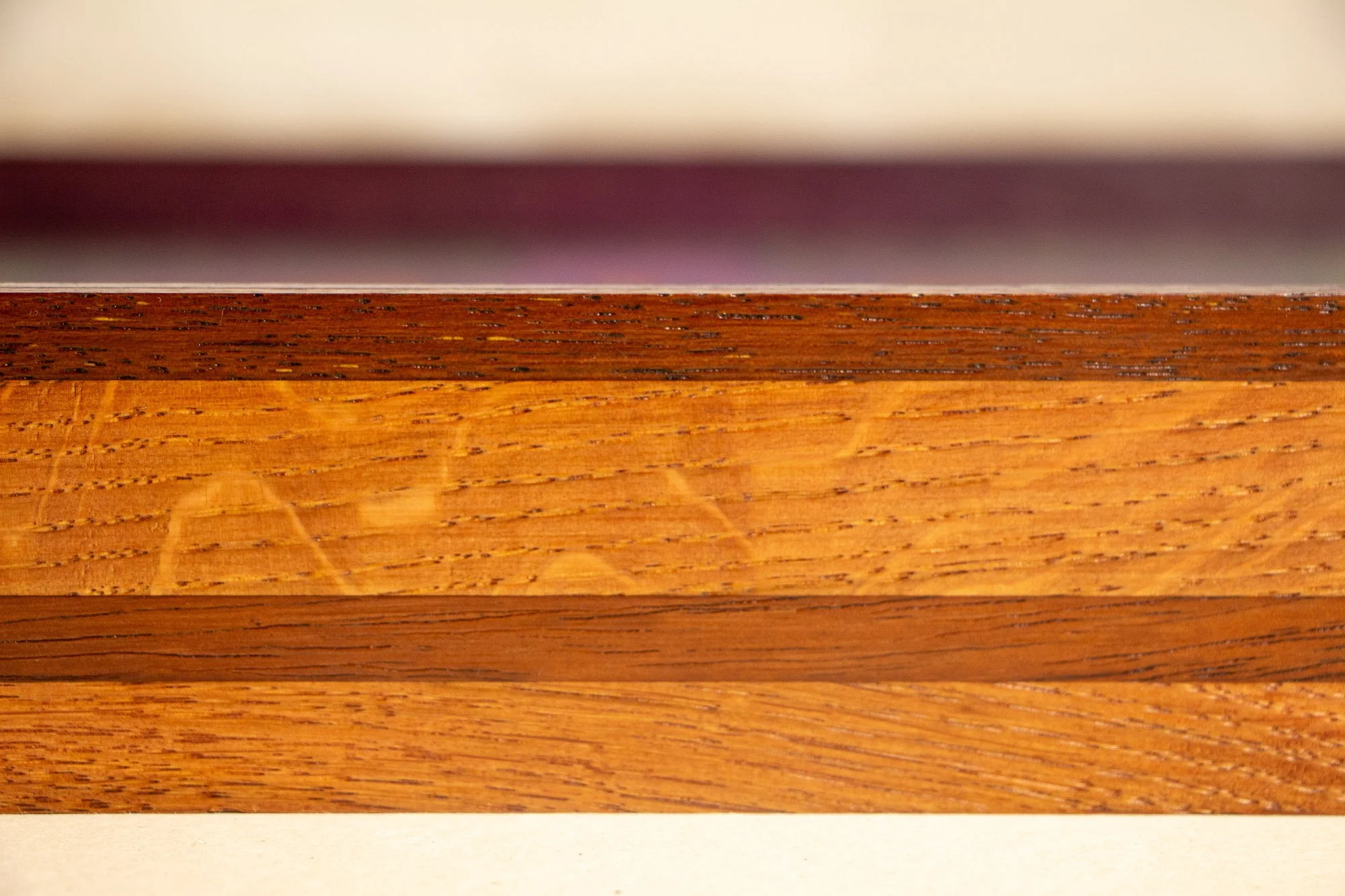 Unseen Signifiers 005 frame detail: close-up of the frame side, emphasizing the figured grain of the warm oak body, the darker horizontal inlay, and the slim dark mahogany band along the top edge. mahogany, oak and beech wood.