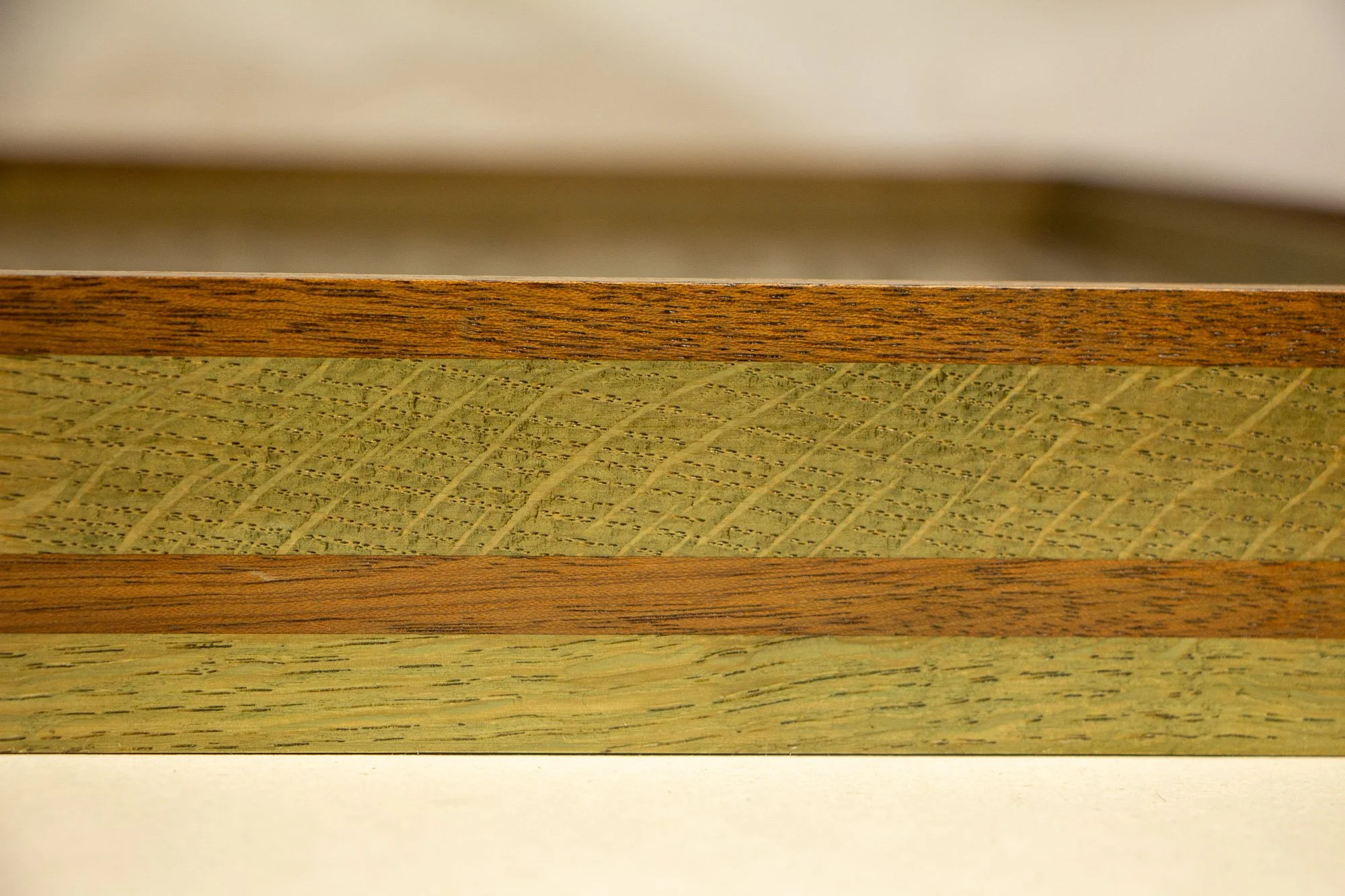 Resonant Syntax 002 frame: horizontal close-up of the frame profile, showing alternating mahogany and oak bands in a mint, blue, and pink rhythm with natural grain throughout