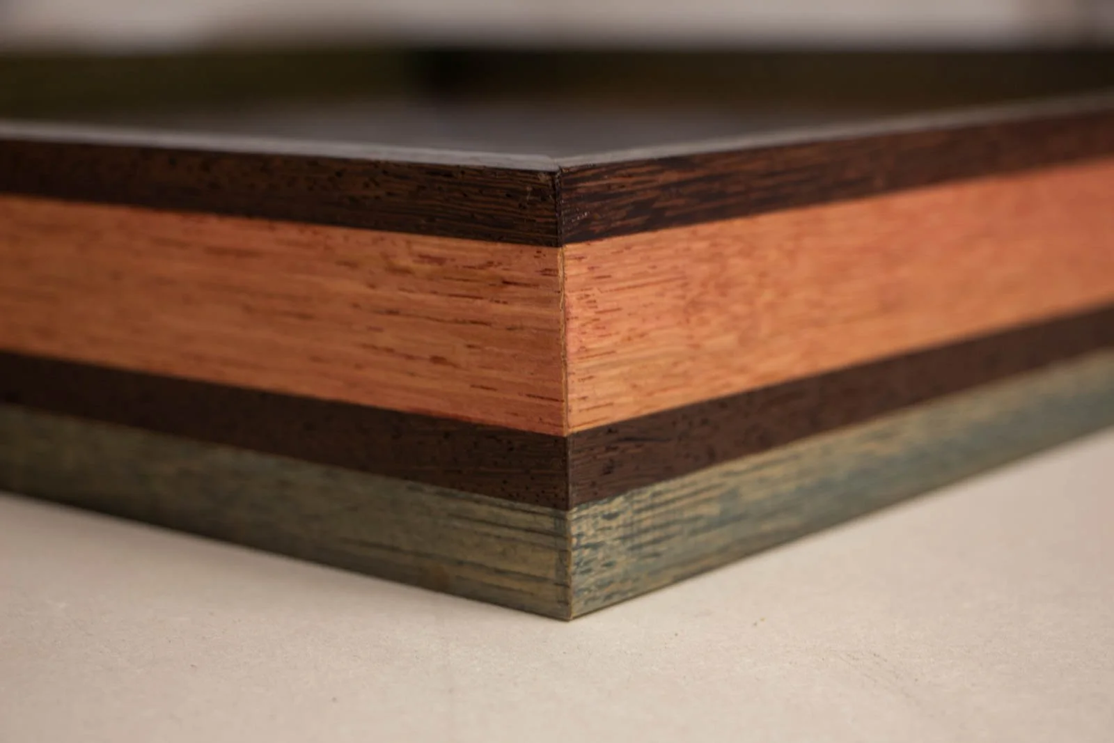 Silence’s Caesura 002 frame: outside mitre, three-tier stack with a deep wengé cap, centered mahogany band, and cool olive-stained oak base; crisp 45° join, satin sheen