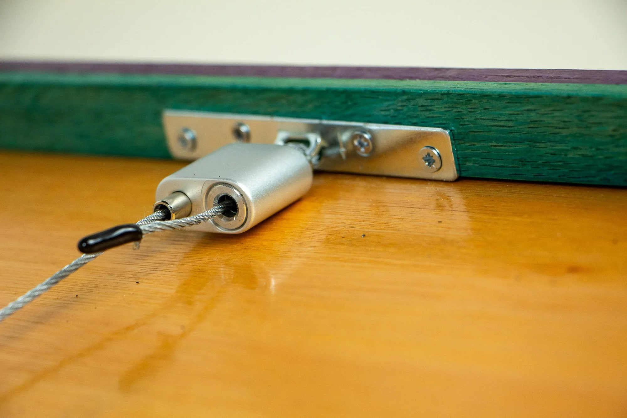 Elusive Cocoon 003 frame: rear hanging detail with silver cable hardware mounted to the mint-toned inner rim, backed by the meranti plywood panel within the layered purple-toned frame.