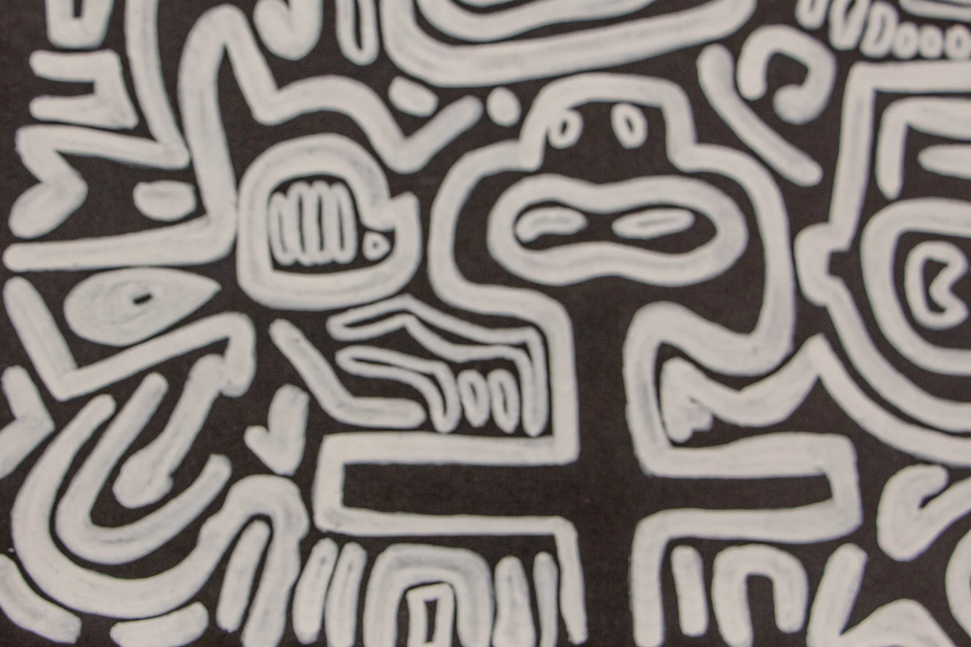 Turbulent Aegis 002 artwork detail: close-up of a rounded white-lined figure on a dark ground, surrounded by angular forms, arrows, and layered symbols within the dense web-like composition.