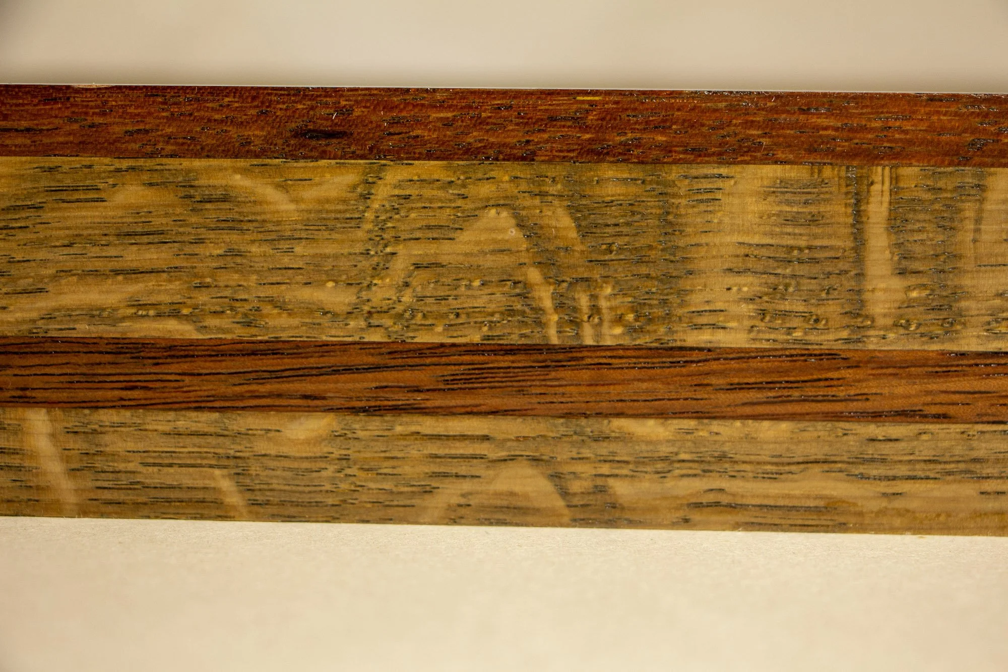 Unseen Signifiers 001 frame detail: horizontal macro of the frame side, focusing on the grain and tonal variation of the lighter oak and the darker central inlay. mahogany, oak and beech wood.