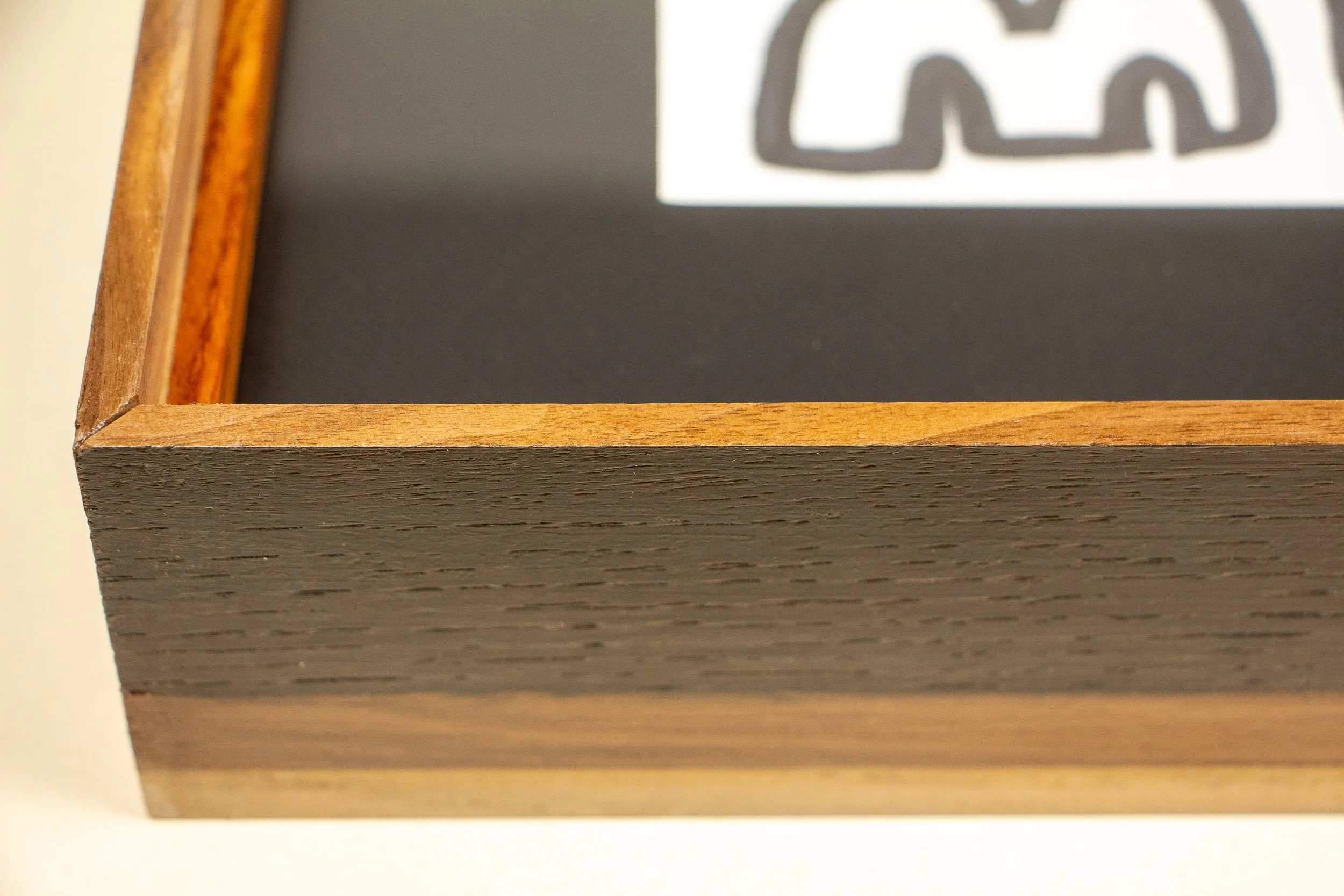 Mêlée of Discovery 002 frame: corner detail from the front, where the dark outer frame meets the warm inner lip and black mount, revealing the work’s precise layered construction.