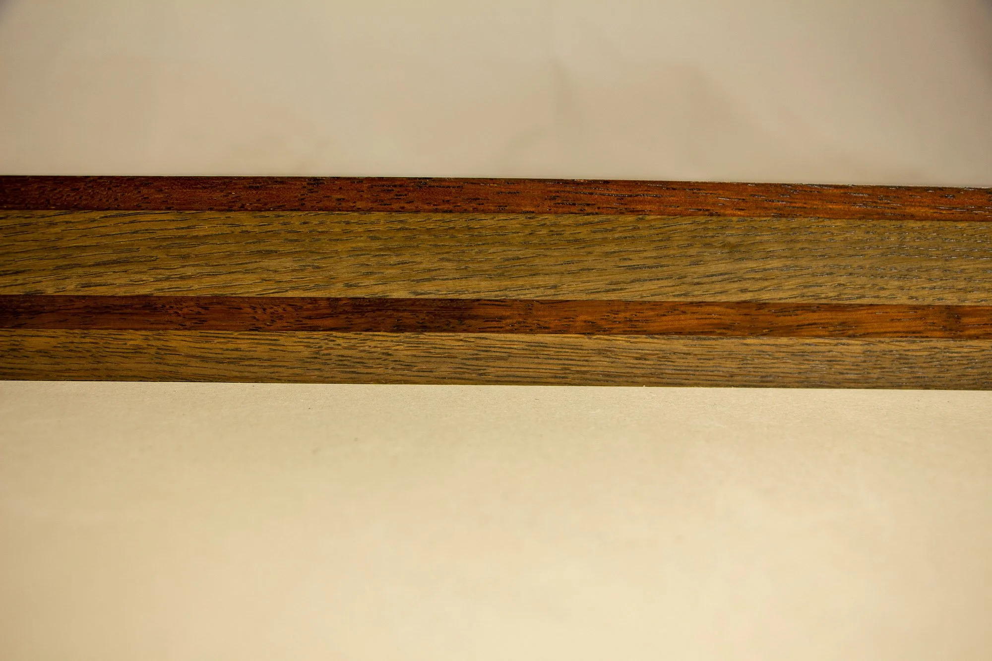 Unseen Signifiers 001 frame detail: straight-on close-up of the layered frame, highlighting the long horizontal rhythm of the wood bands and the subtle variation in grain and finish. mahogany, oak and beech wood. mahogany, oak and beech wood.