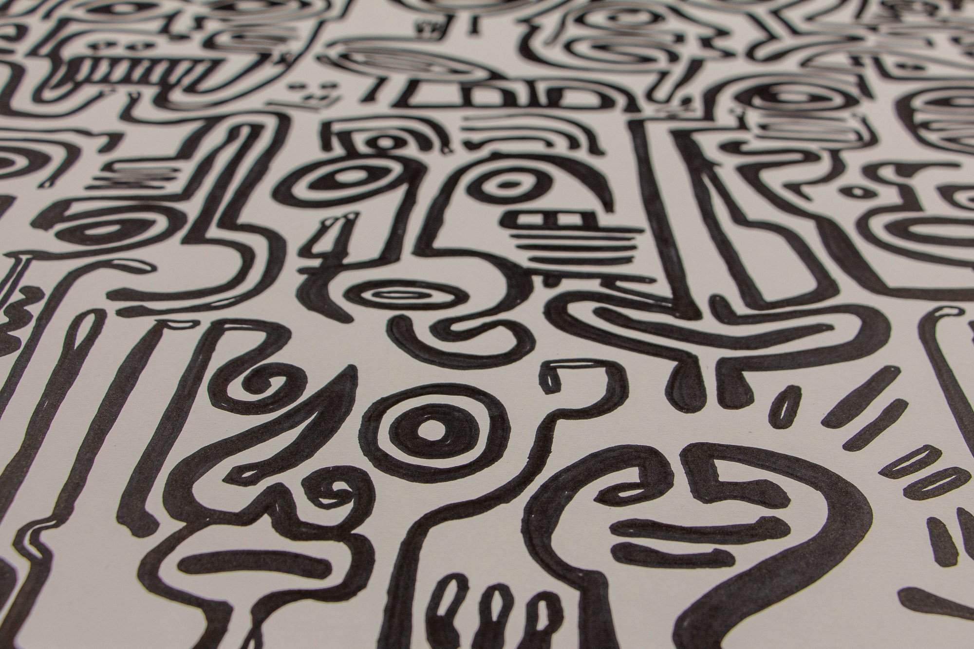 Veiled Alchemist 001 detail: angled view across the drawing, highlighting a central face surrounded by echoing forms, oval eyes, and flowing black linework that creates rhythm, pressure, and quiet instability.