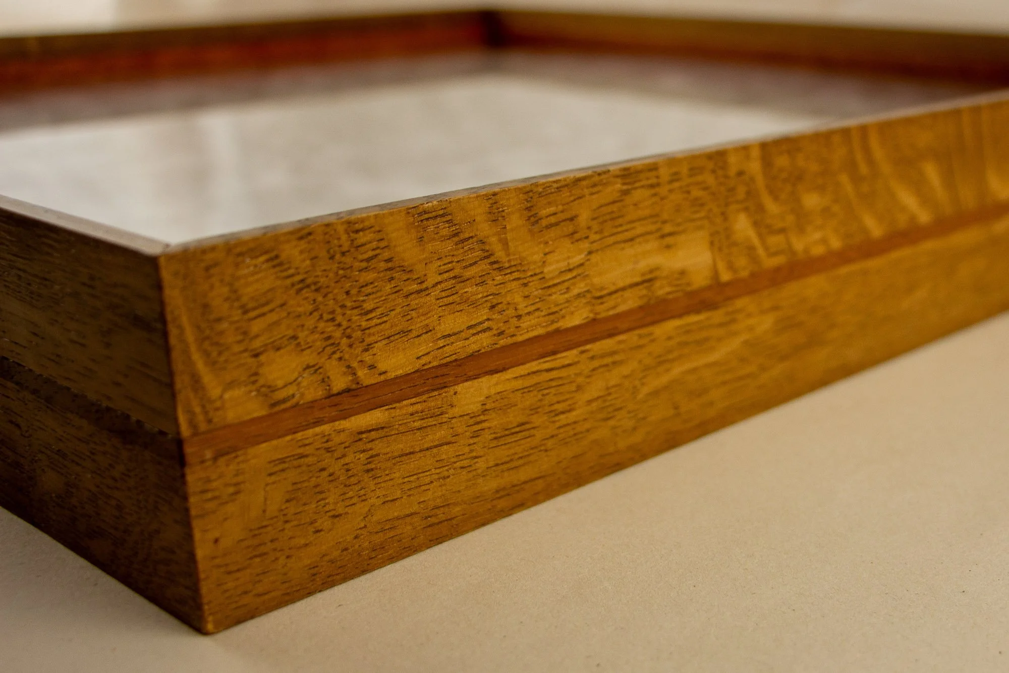 Veiled Alchemist 004 frame detail: angled side view of the Japanese elm frame, showing the warm outer body, the fine reddish inner band, and the floating depth created beneath the glazing.