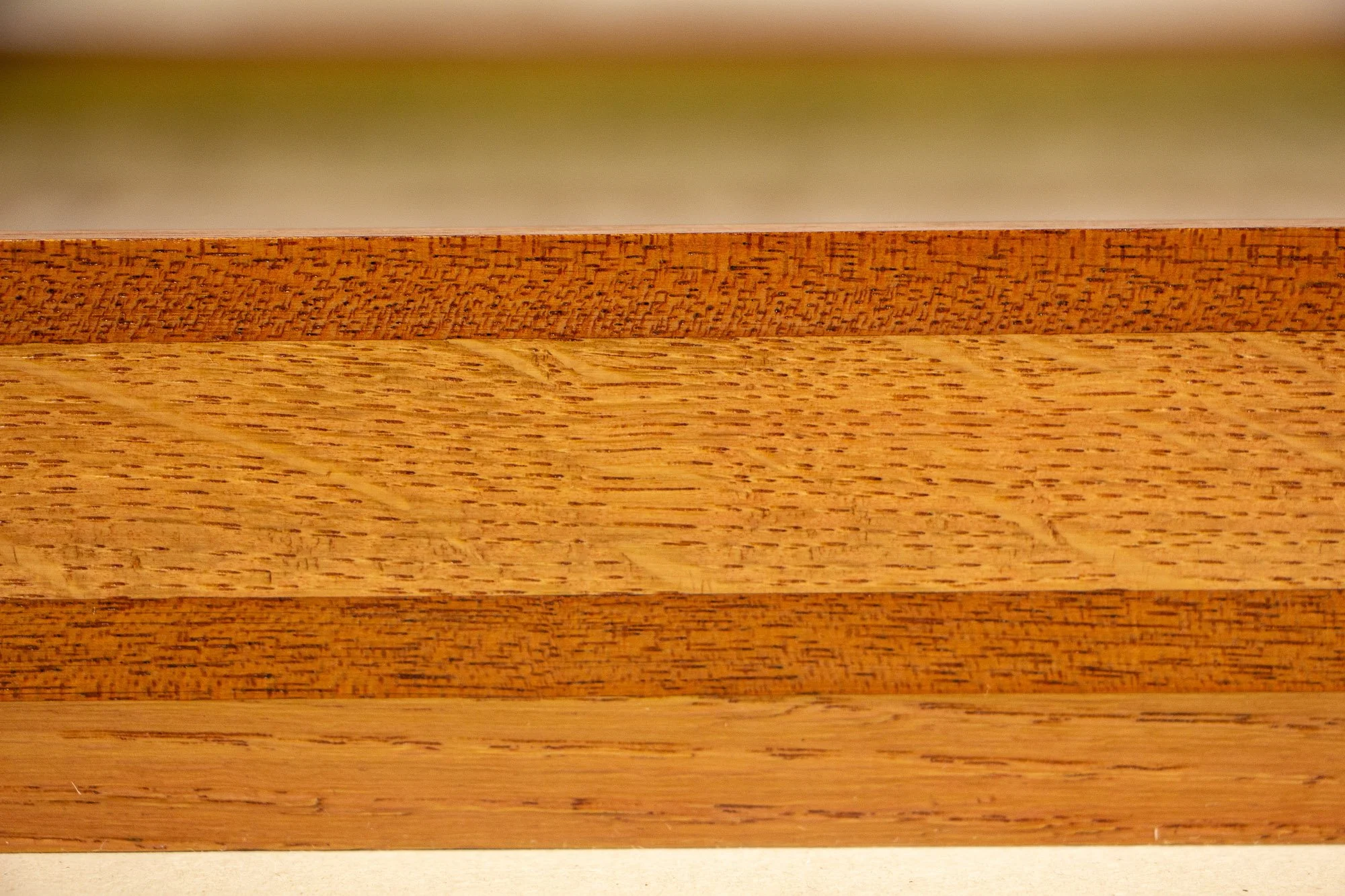 Resonant Syntax 001 frame: macro close-up of the frame side, with stacked mahogany and oak layers in shifting pink, mint, and blue tones and crisp finished edges