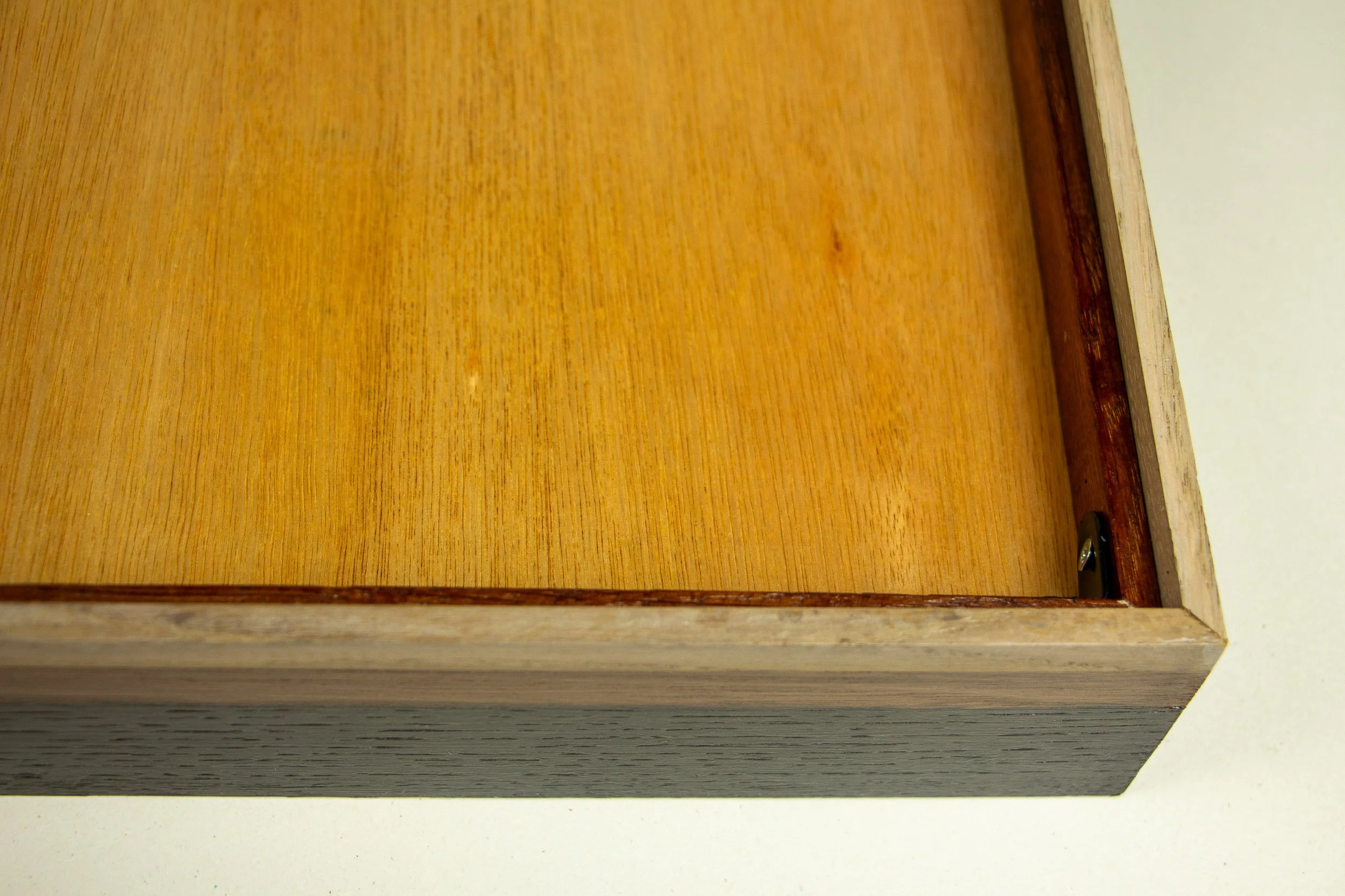 Mêlée of Discovery 002 frame: rear corner detail of the frame, showing the backing board, reddish inner rim, pale outer wood, and the recessed structure that holds the work in place.