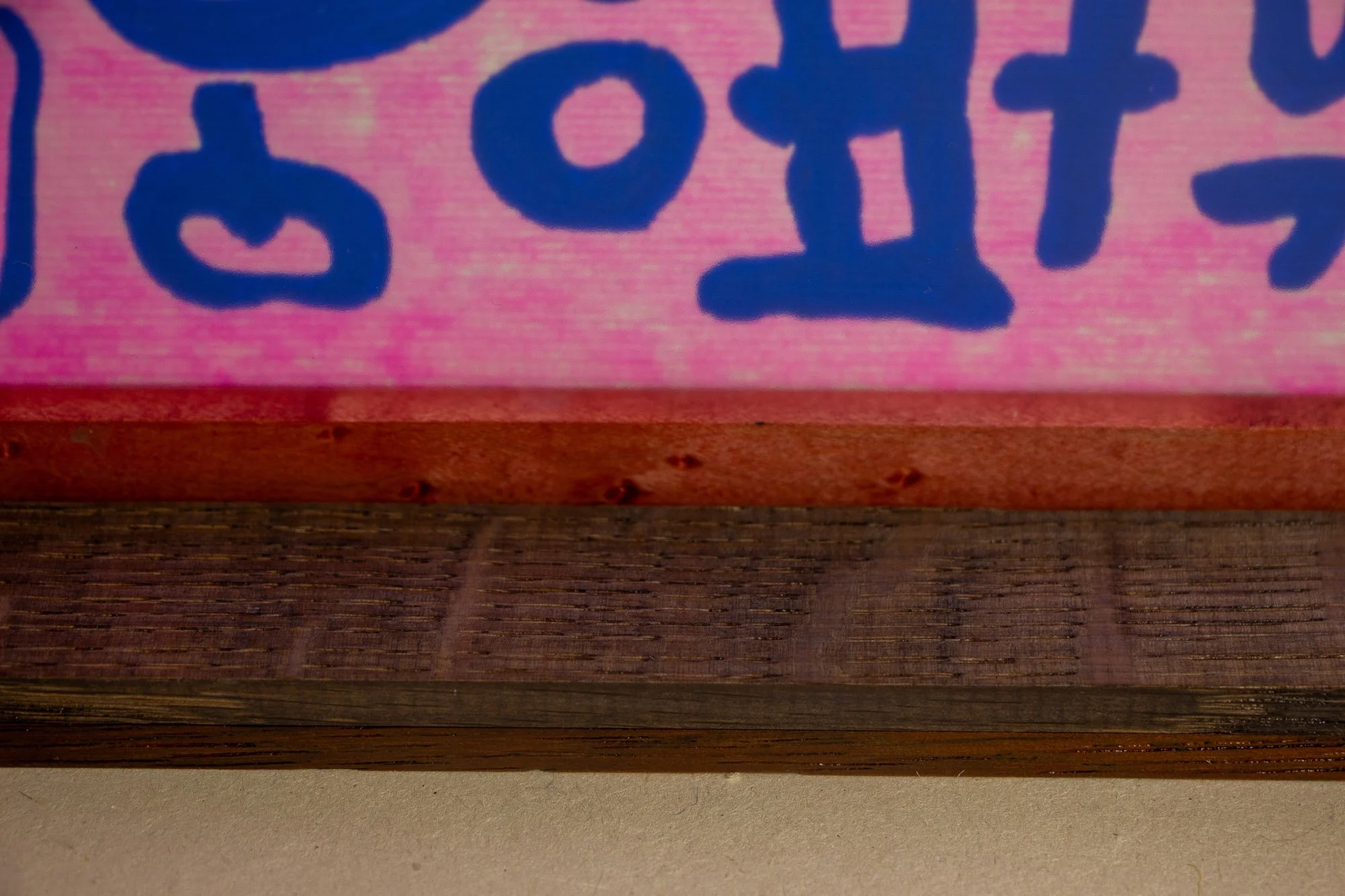 Unseen Signifiers 007 frame detail: horizontal close-up of the lower inner frame, showing the reddish inner strip, dark wood banding, and the pink ground with blue markings beneath the glazing. mahogany, oak and beech wood.