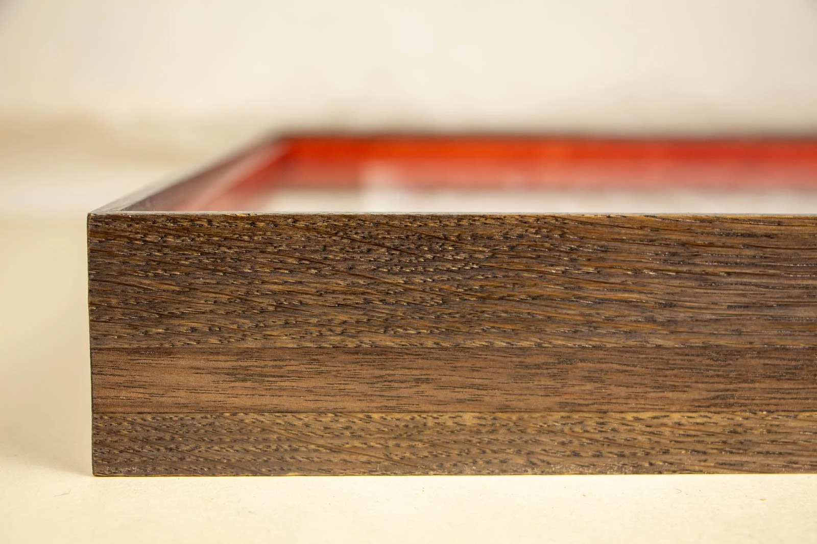 Flux Impromptu 003 frame: end elevation, dark oak outer rail with a centered walnut band; smooth satin finish; faint Granada-red inner liner beyond the glass