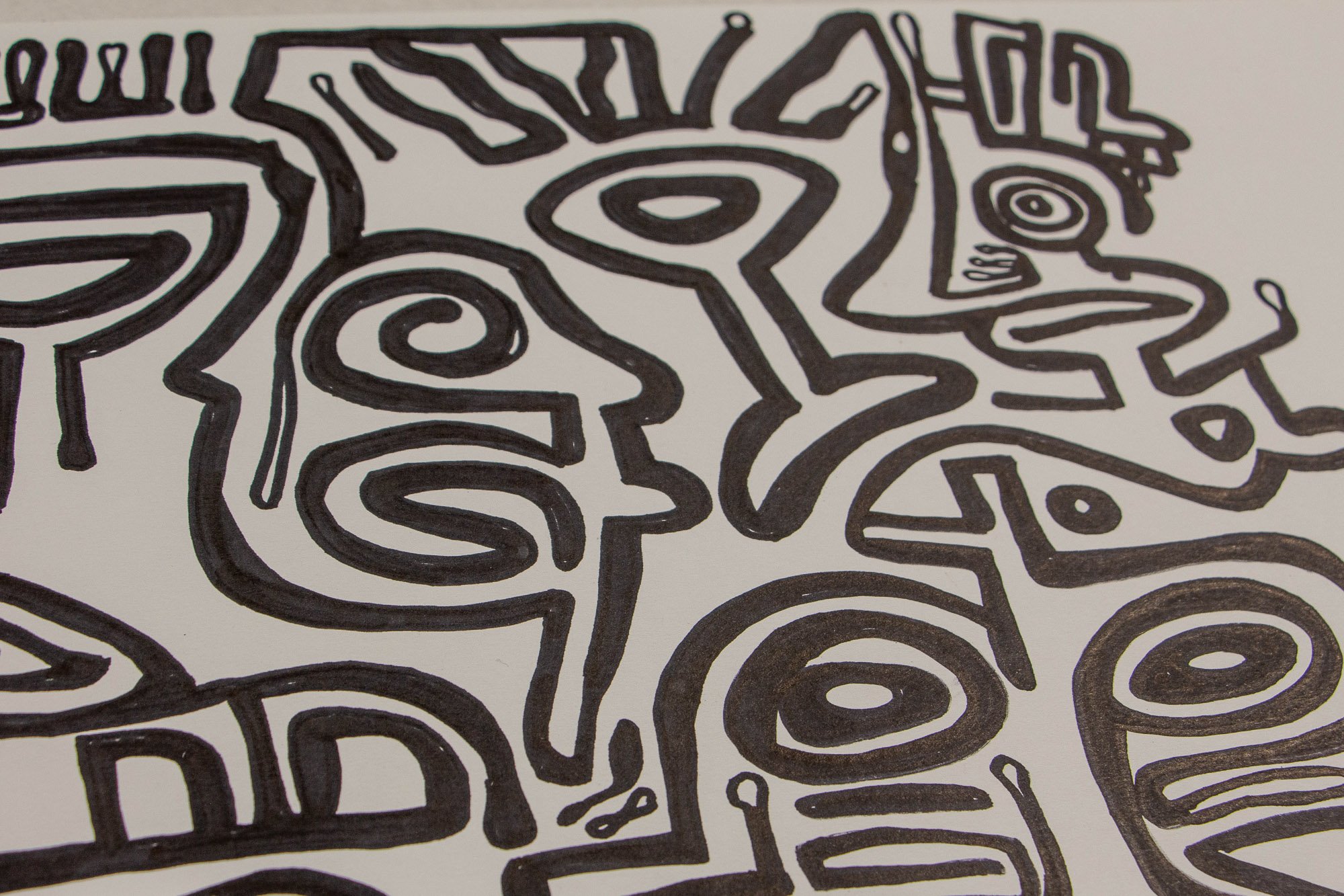 Veiled Alchemist 001 detail: close-up of adjoining heads and creature-like forms, with a large central eye, curling contours, and compact symbolic marks that give the composition a restless but controlled energy.