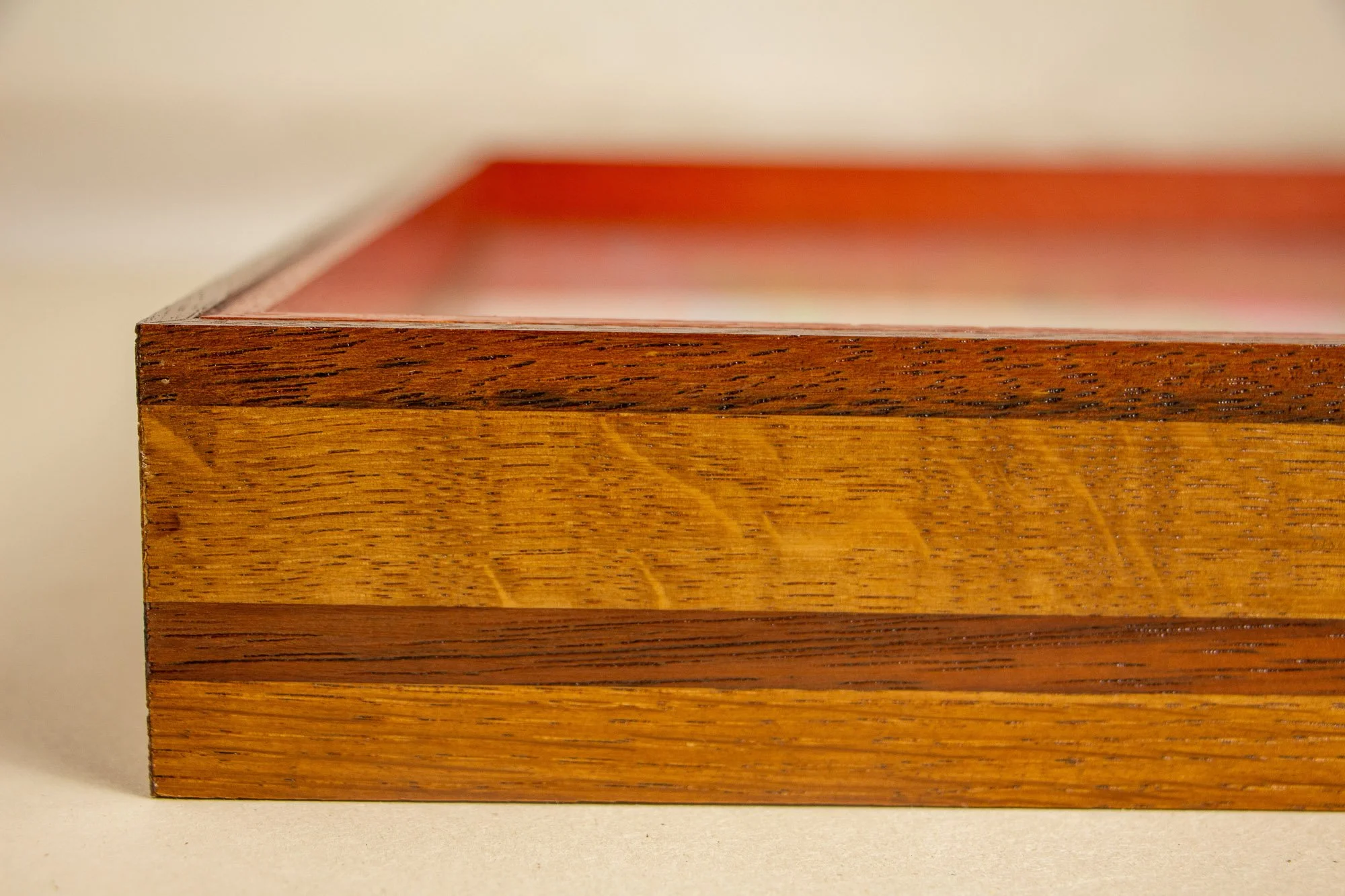 Unseen Signifiers 008 frame detail: close-up of the front frame edge, showing the layered warm wood bands and the crisp upper profile beneath the glazing. mahogany, oak and beech wood.