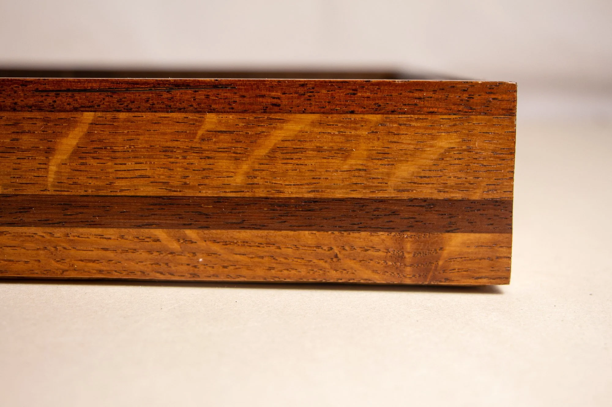 Turbulent Aegis 002 frame detail: frontal side close-up of the frame, highlighting the stacked wood layers, precise joinery, and the warm amber-brown tonal variation across the profile.