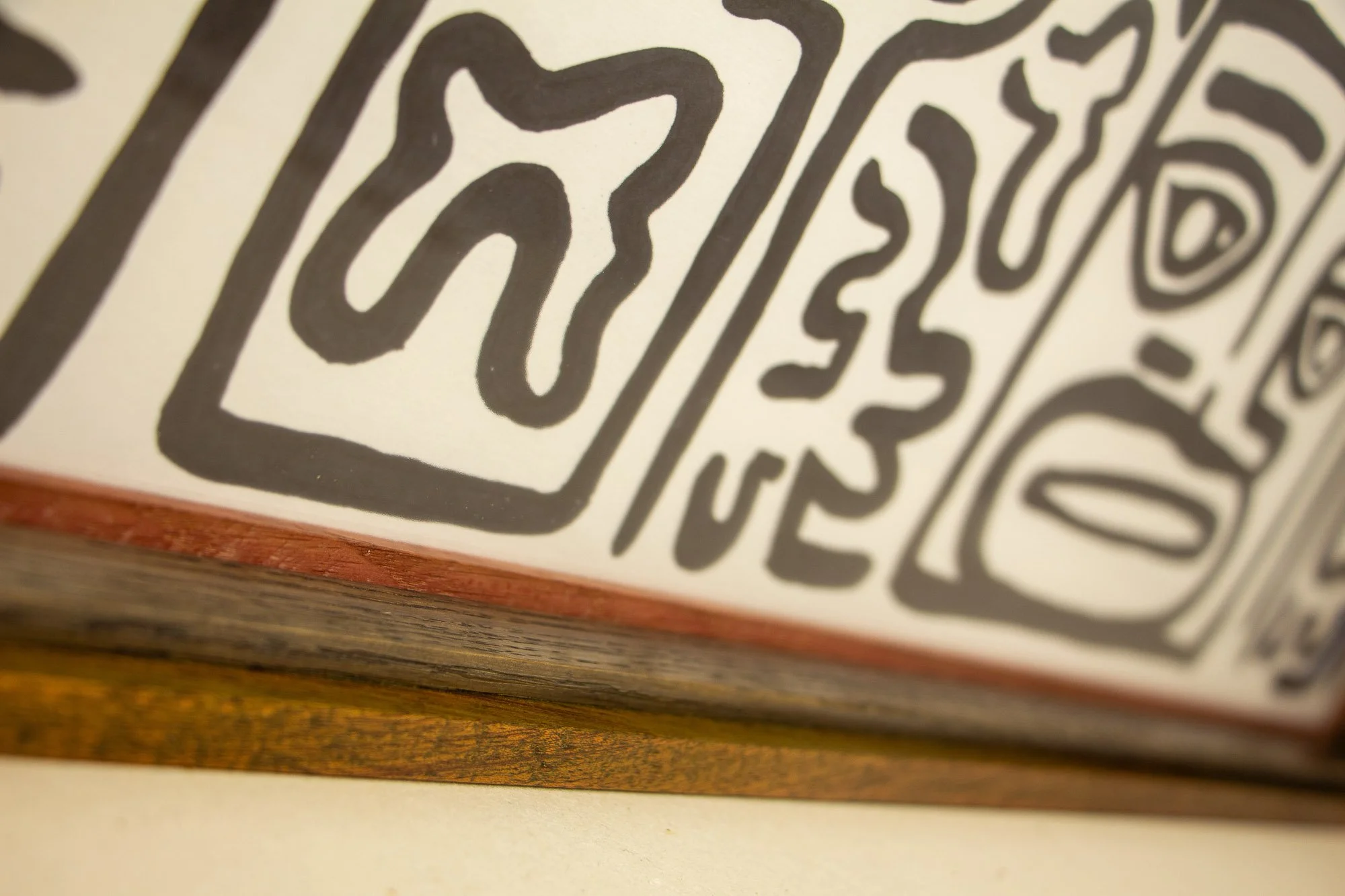 Resonant Syntax 004 frame: oblique lower-edge detail with the artwork surface above, a narrow red inner lip, dark inner oak band, and warm red-brown outer frame