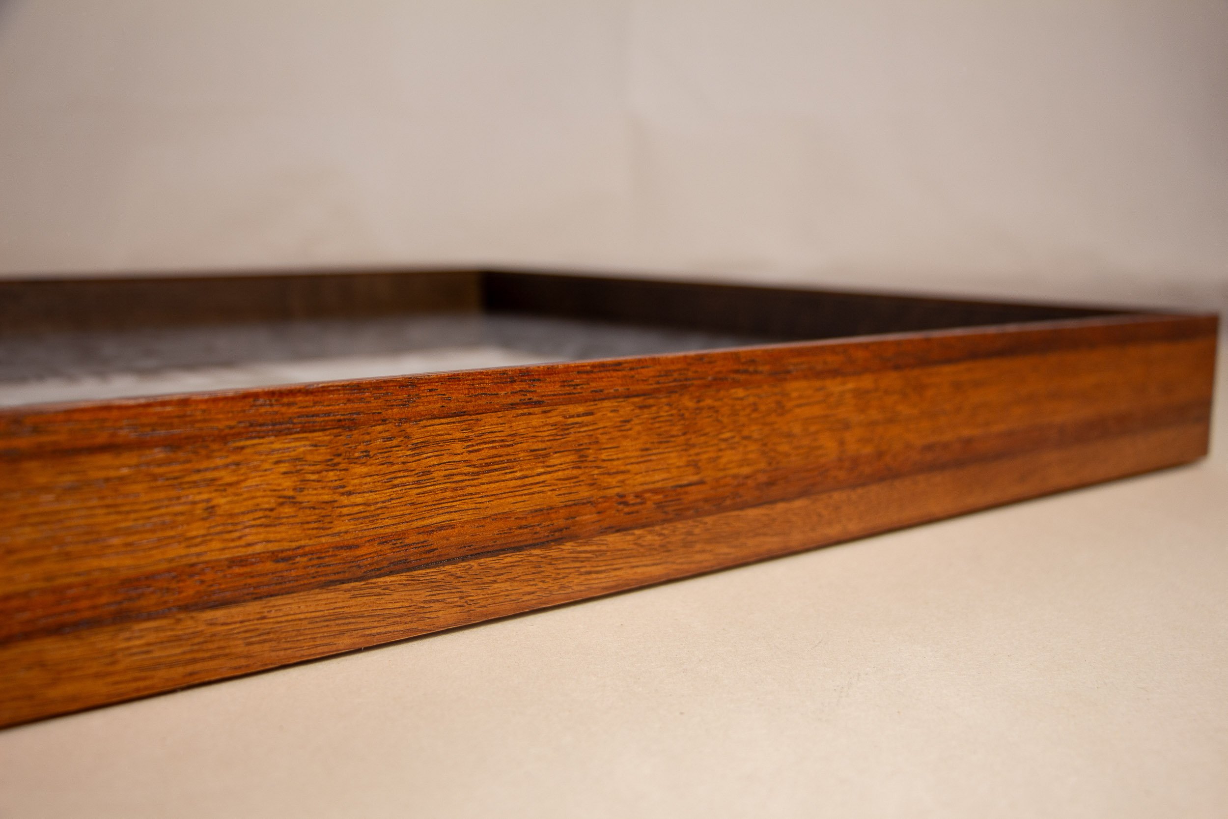 Turbulent Aegis 003 frame detail: low angled side view of the frame, highlighting its elongated profile, warm lacquered surface, visible wood grain, and the calm horizontal movement of the layered construction.