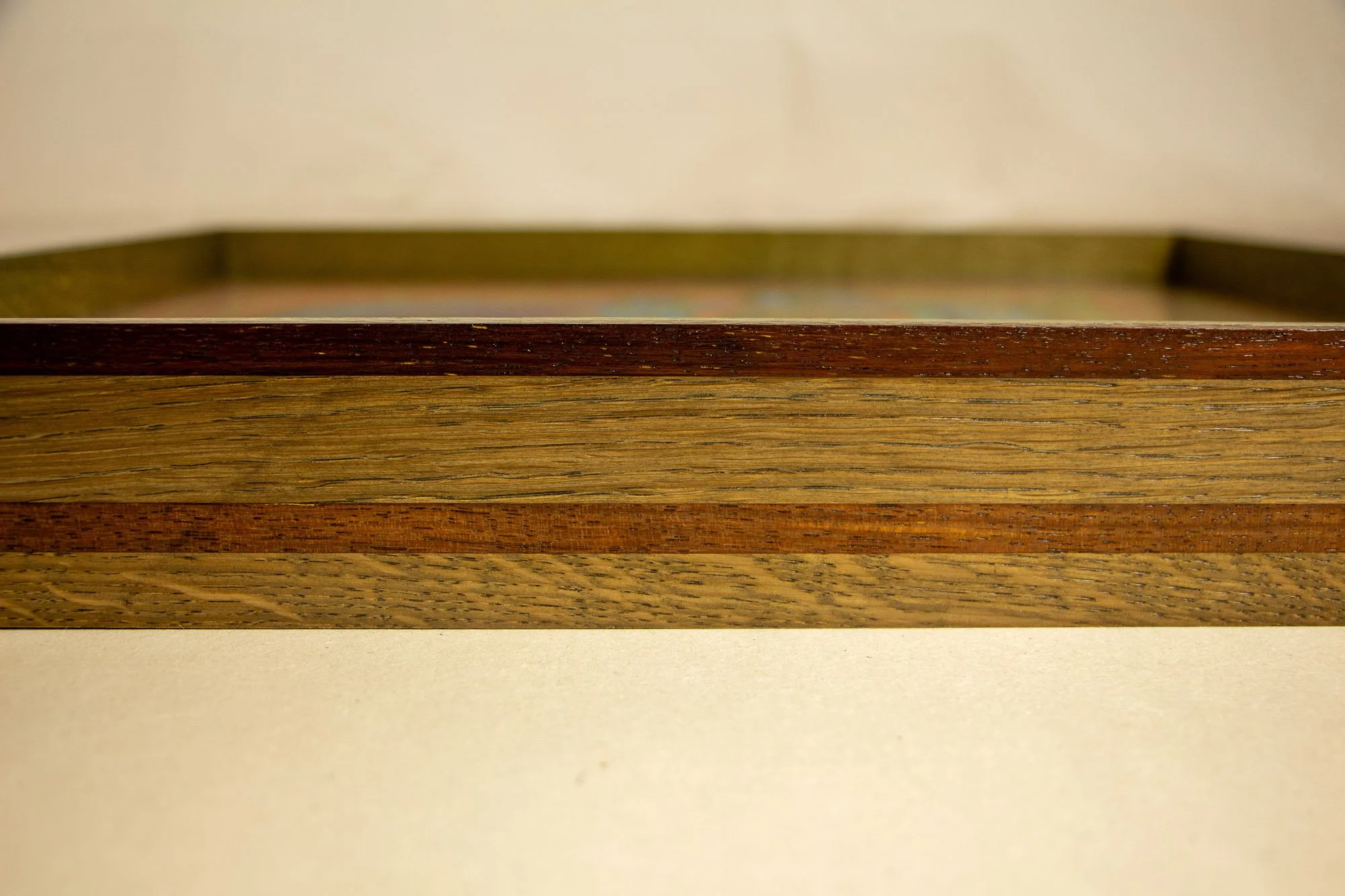 Unseen Signifiers 001 frame detail: front-facing close-up of the frame side, showing the horizontal layering of reddish-brown and light oak tones across the full width. mahogany, oak and beech wood.