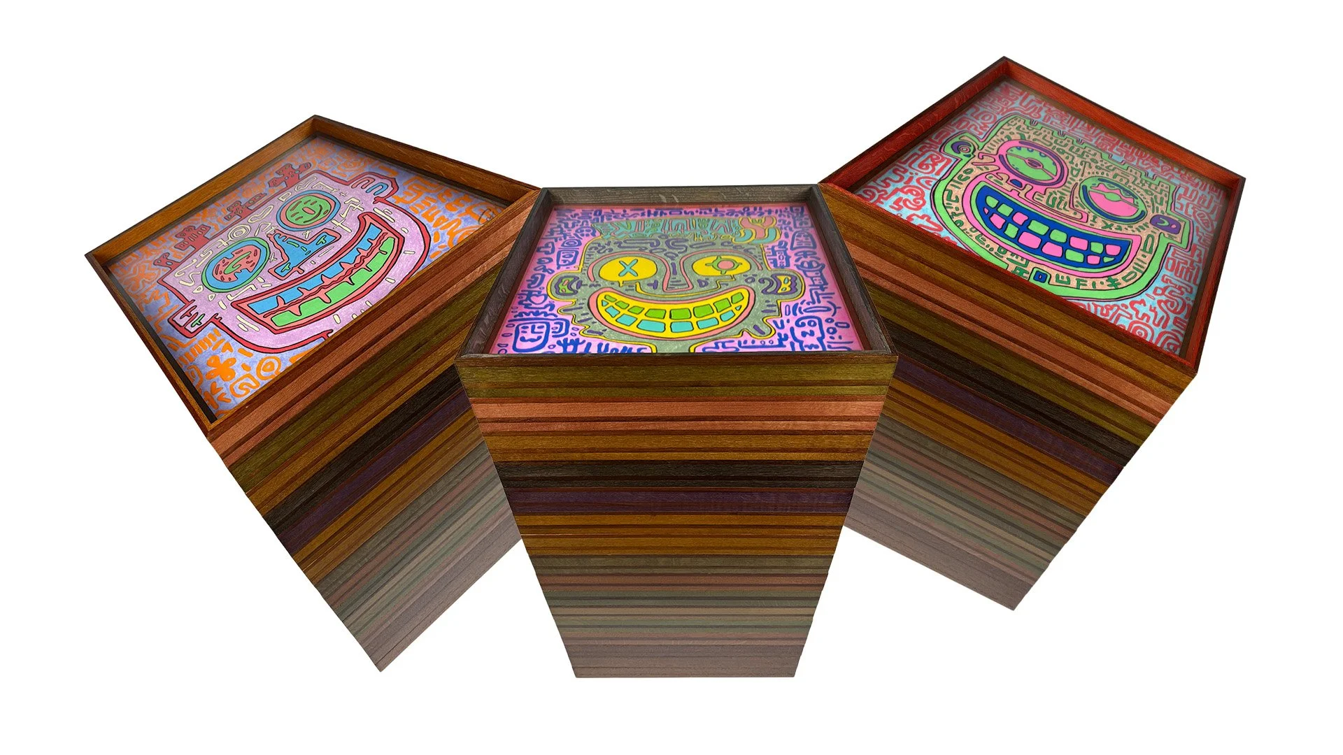 Three wooden boxes with colorful, graffiti-style artwork on the lids, featuring smiling cartoon faces with exaggerated features and vibrant doodles.
