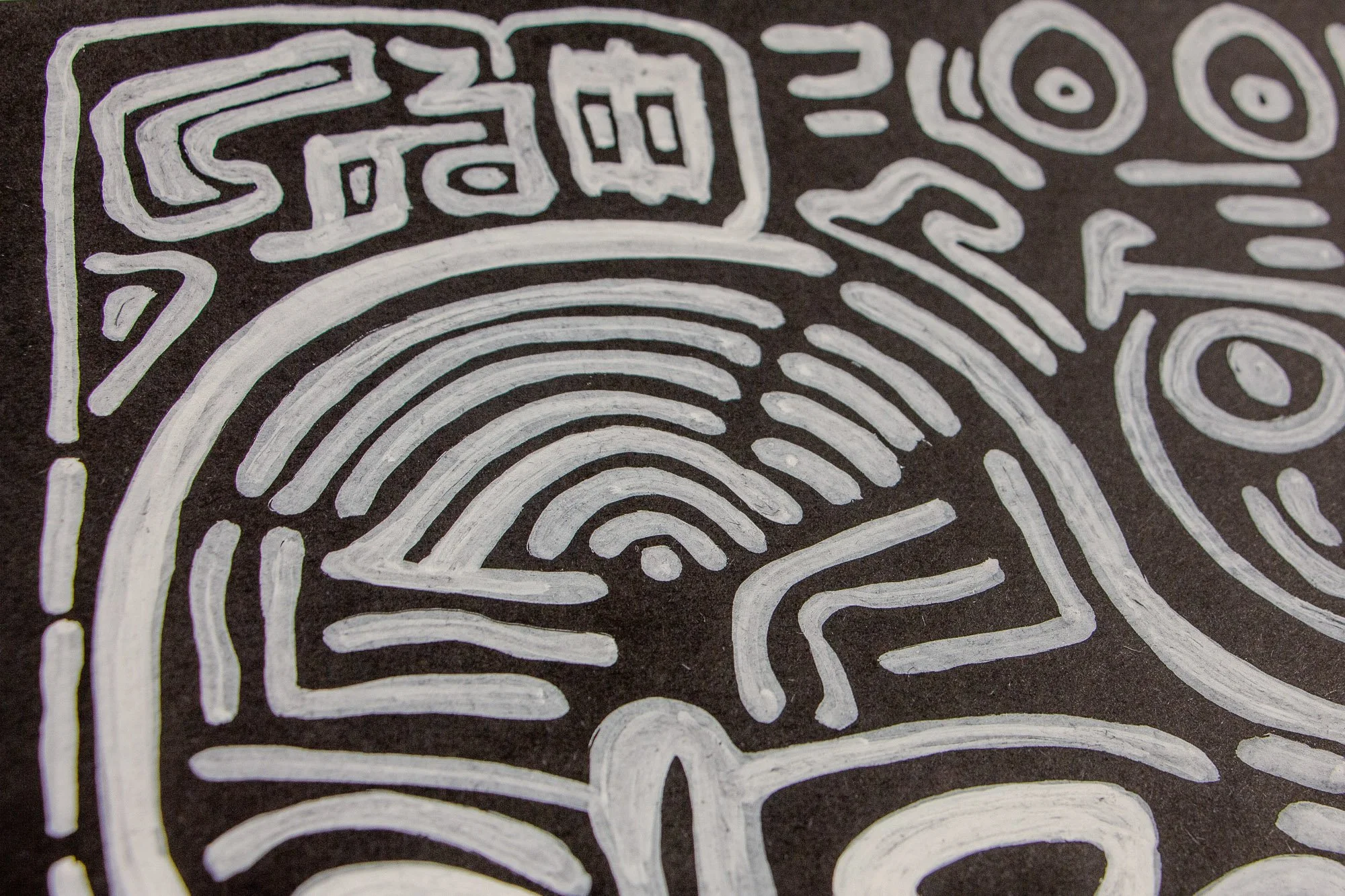 Mêlée of Discovery 001 detail: close-up of the corner area featuring a concentric eye form, boxed symbol-like marks, and a partial face, drawing attention to the layered visual language of the work.