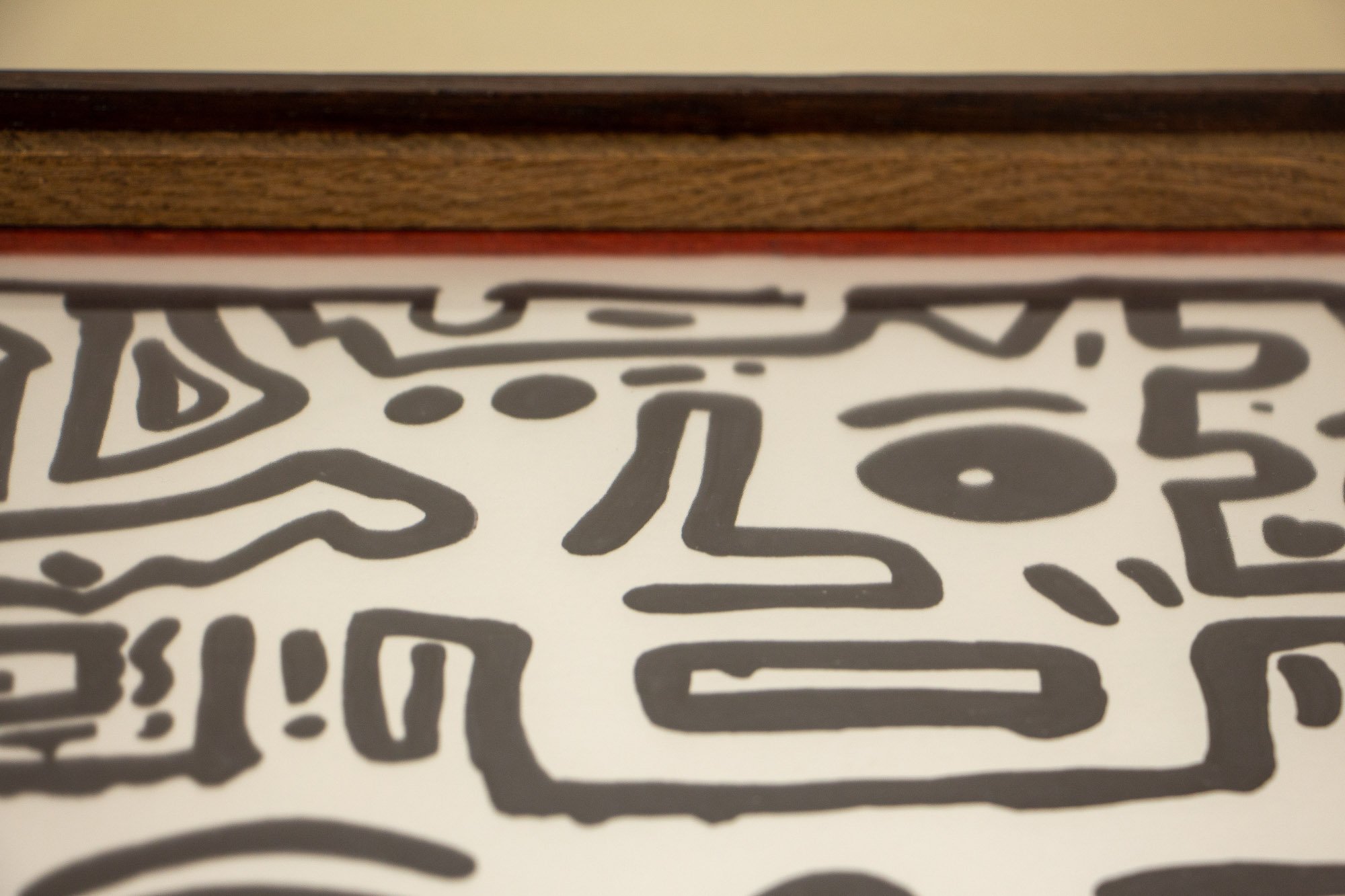 Elusive Cocoon 001 frame: lower sight edge with red inner liner above the pale ash-toned band and darker outer rail, seen beneath the black ink drawing.