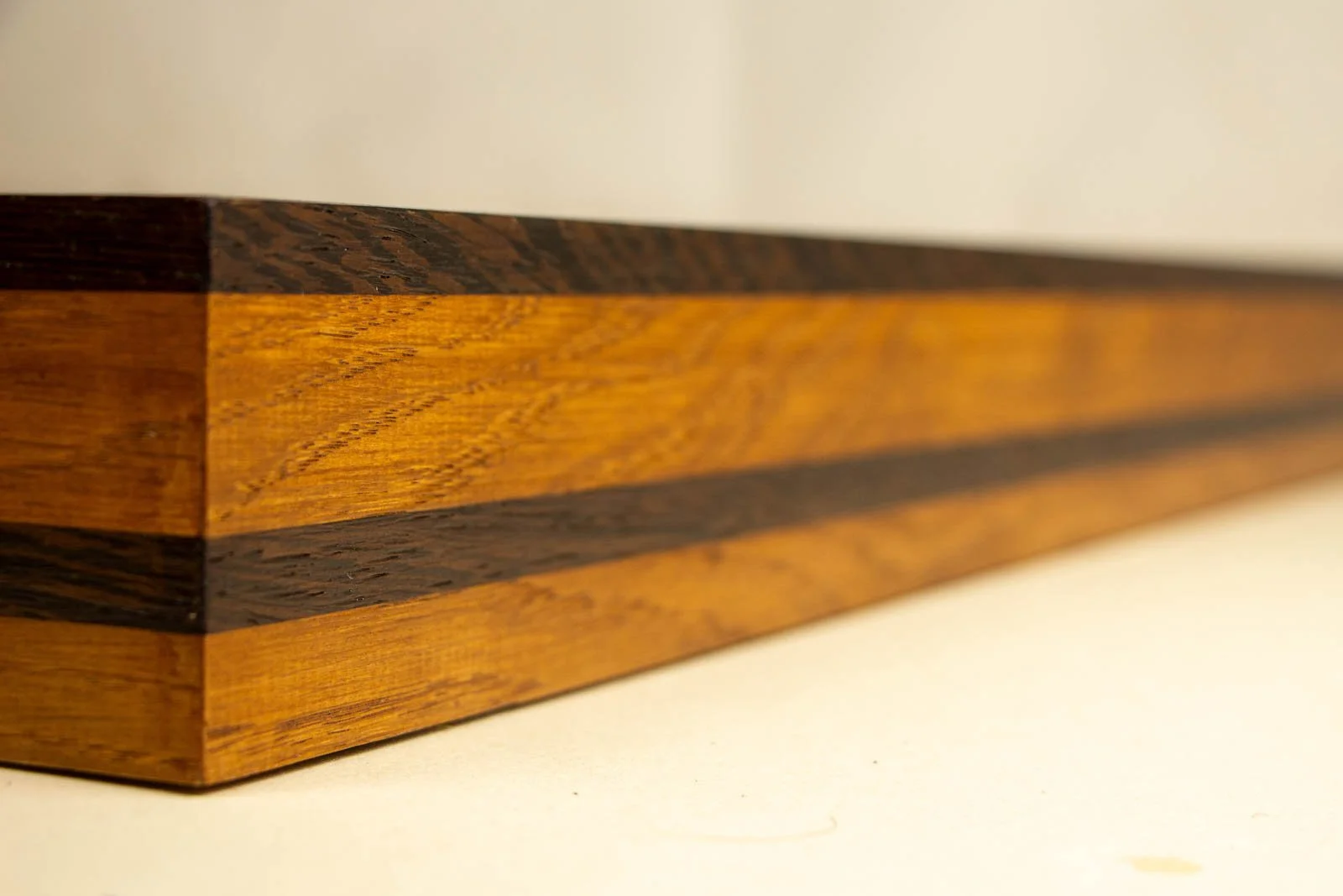 Metamorphic Entwining 003 frame: long elevation of the oak side with a small central knot; cap and mid-band read cleanly against the golden field