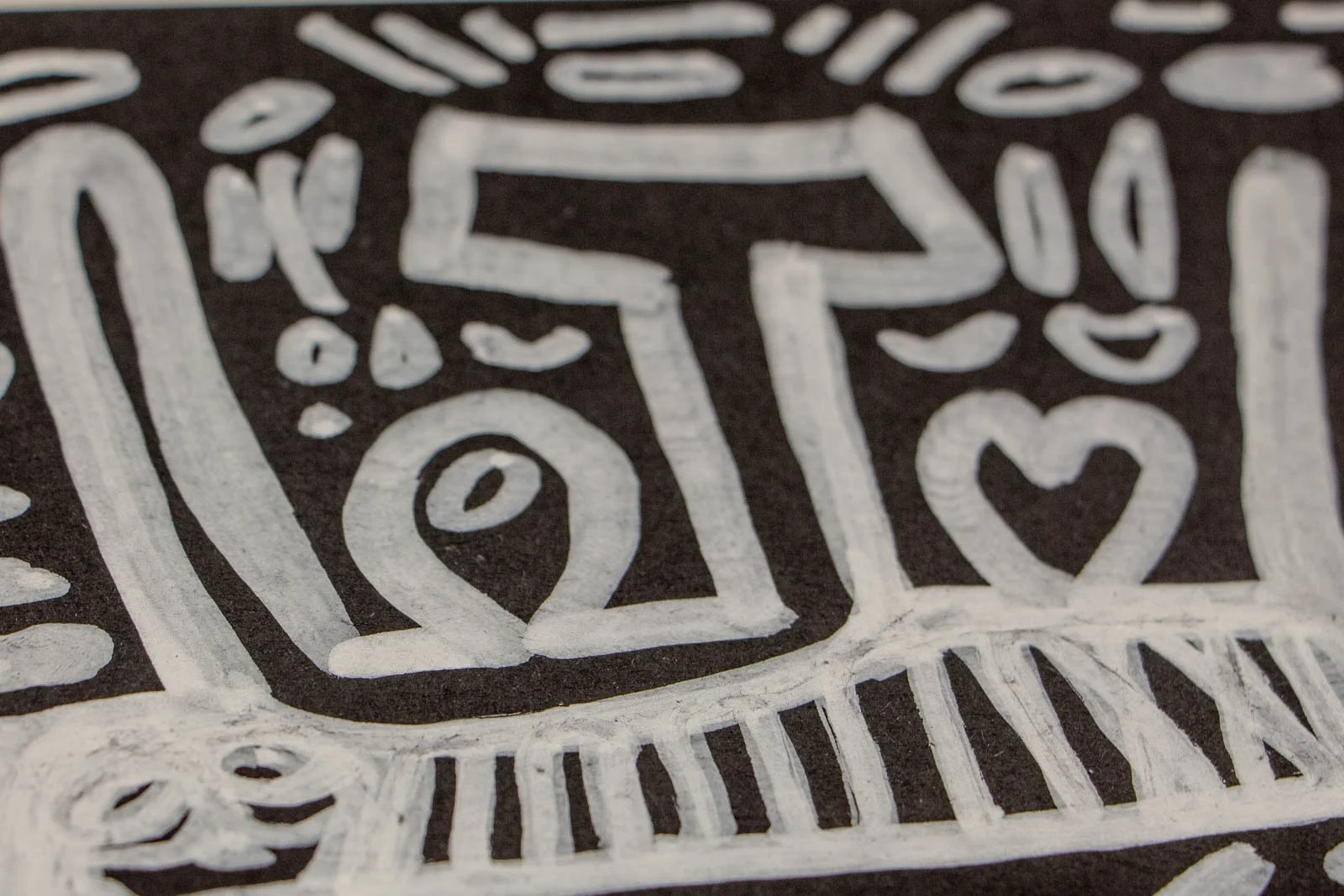 Metamorphic Entwining 001 detail: glyphic T form with dotted halo and a small heart beside a framed eye, textured layering, white ink on black paper