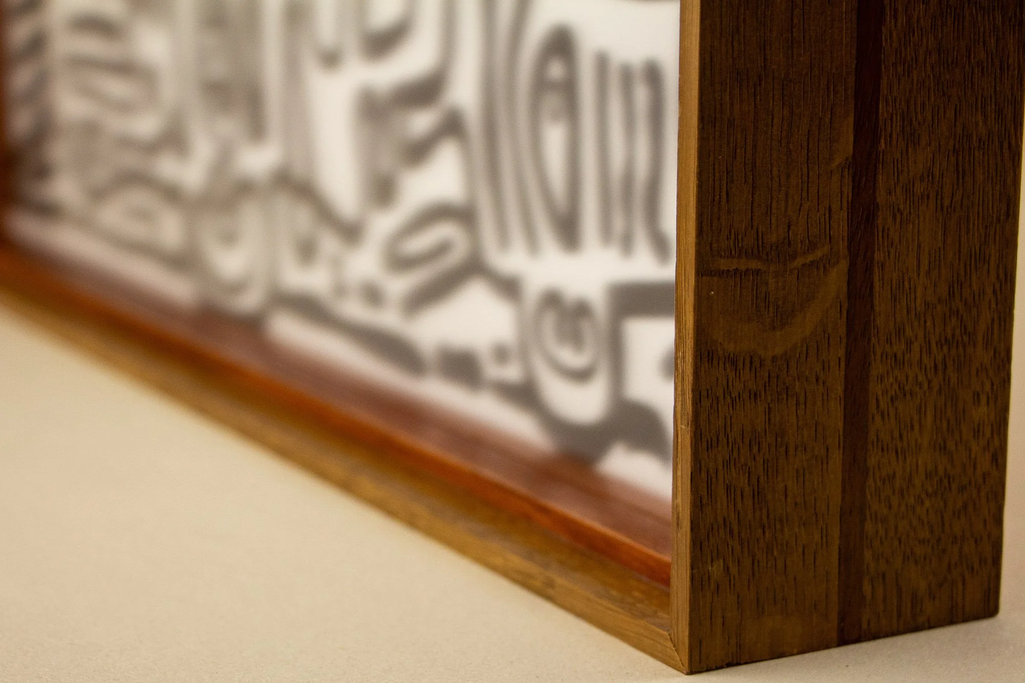 Close-up of a wooden picture frame with intricate black-and-white artwork behind glass.