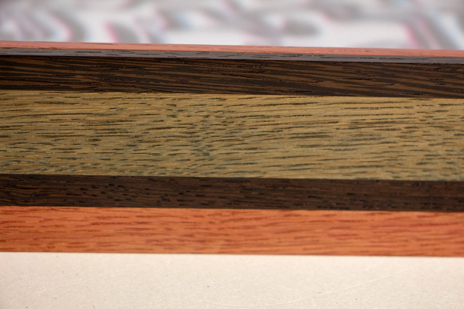 Silence’s Caesura 001 frame: long side, calm, even oak grain between the wengé ribbon and the mahogany base; smooth satin finish along the top lip