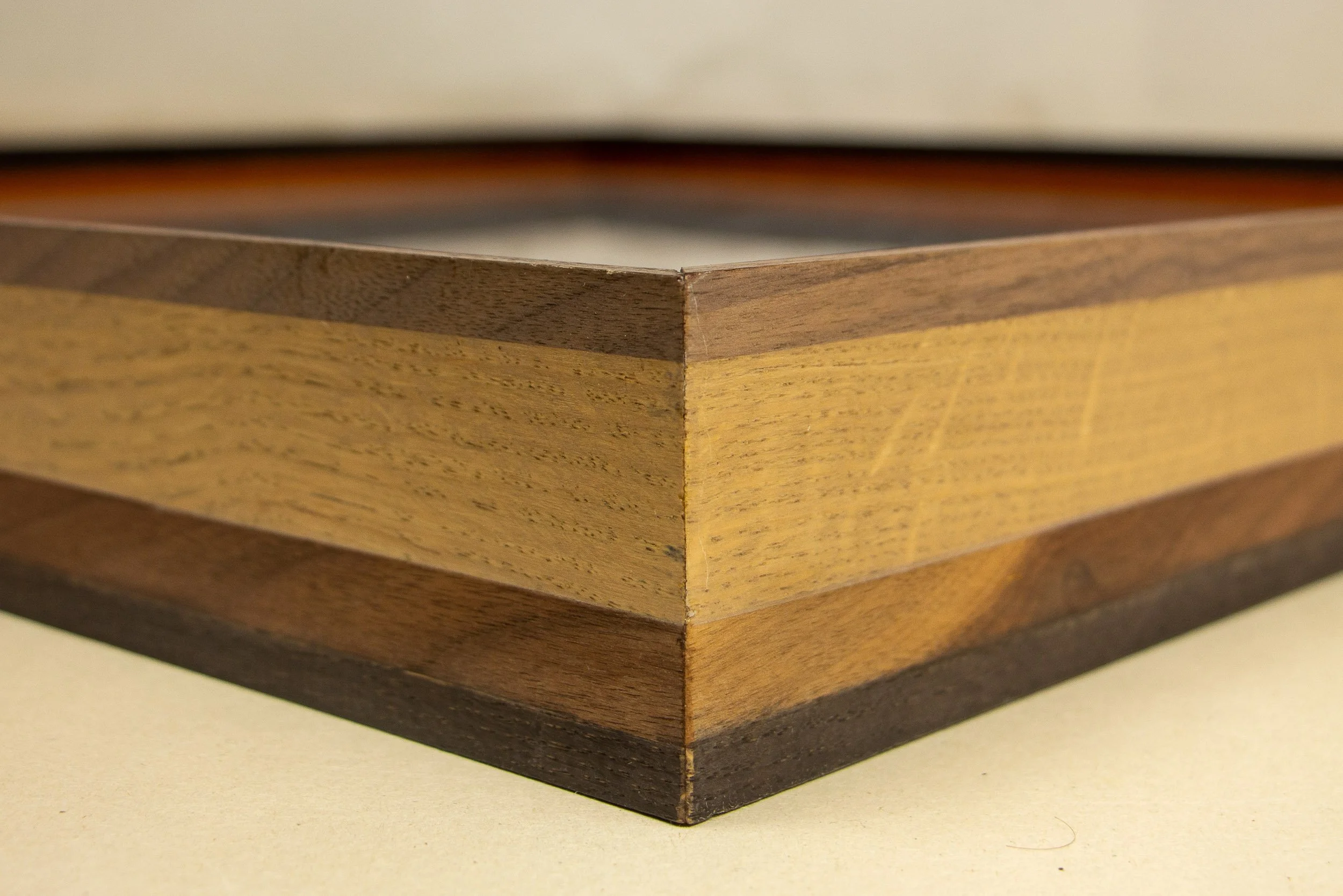 005; Mêlée of Discovery 003 frame: close-up of the frame profile, where subtle grain patterns move across the light central strip and darker surrounding bands.