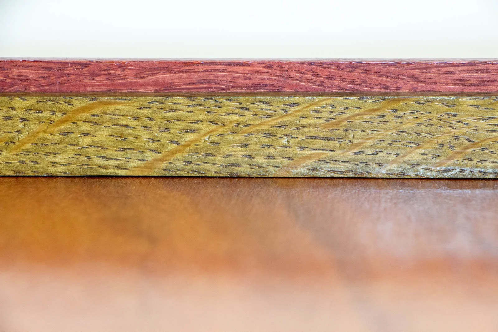 Formless Equation 004 frame: horizontal view of olive-green inner spacer with pronounced grain beneath a red-toned top rail